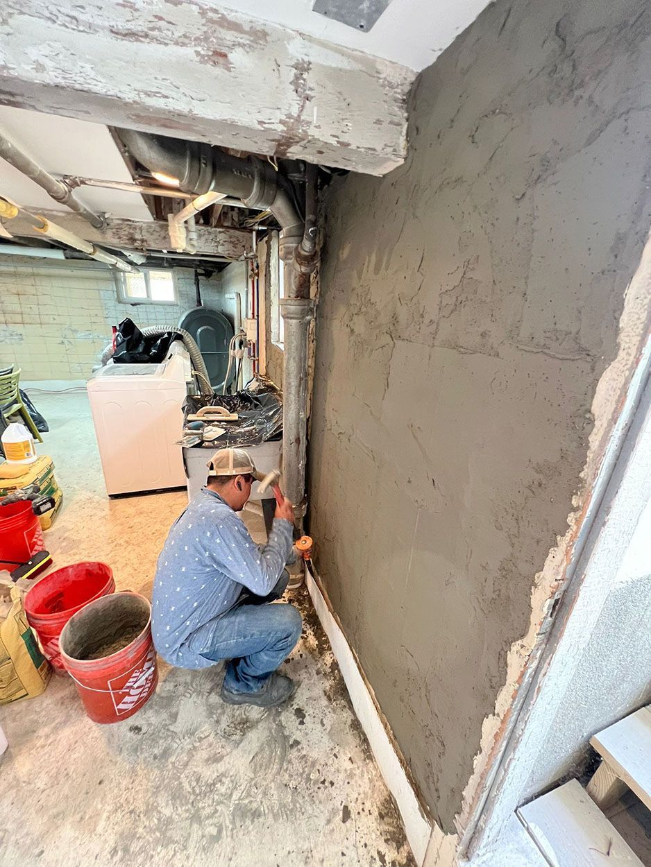 A man is working on a wall in a basement