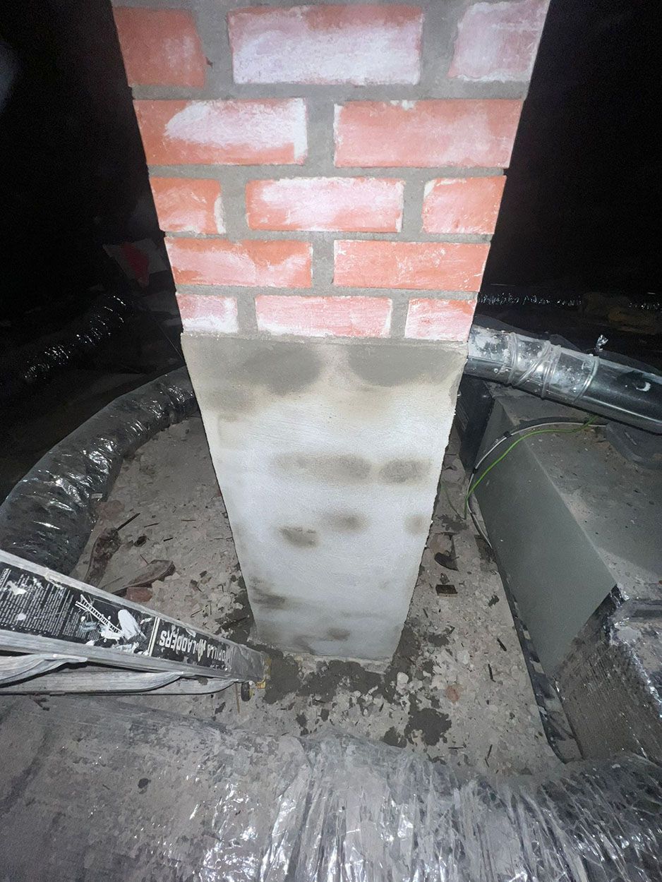 A brick chimney is being built in a dark room
