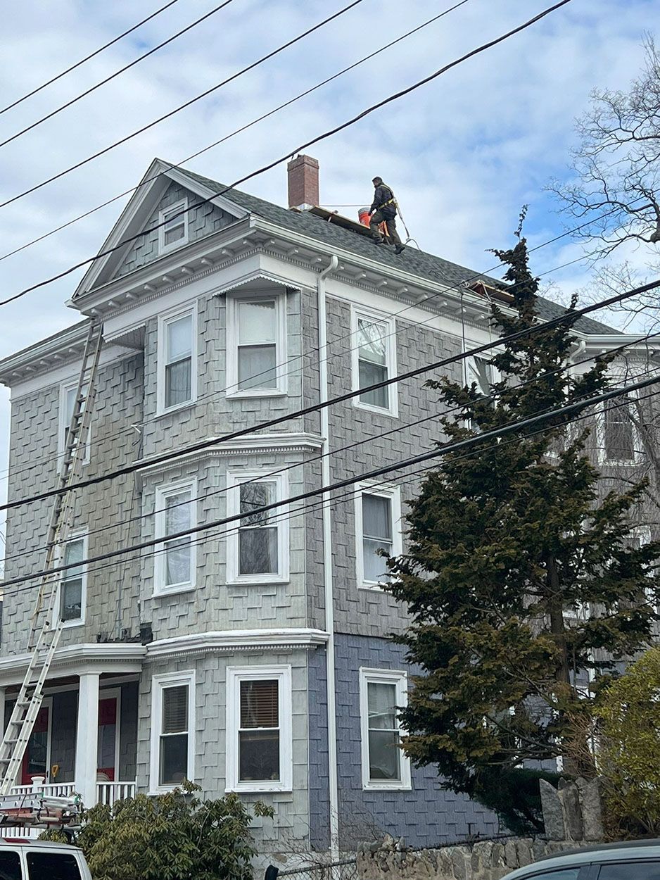 A man is working on the roof of a large house