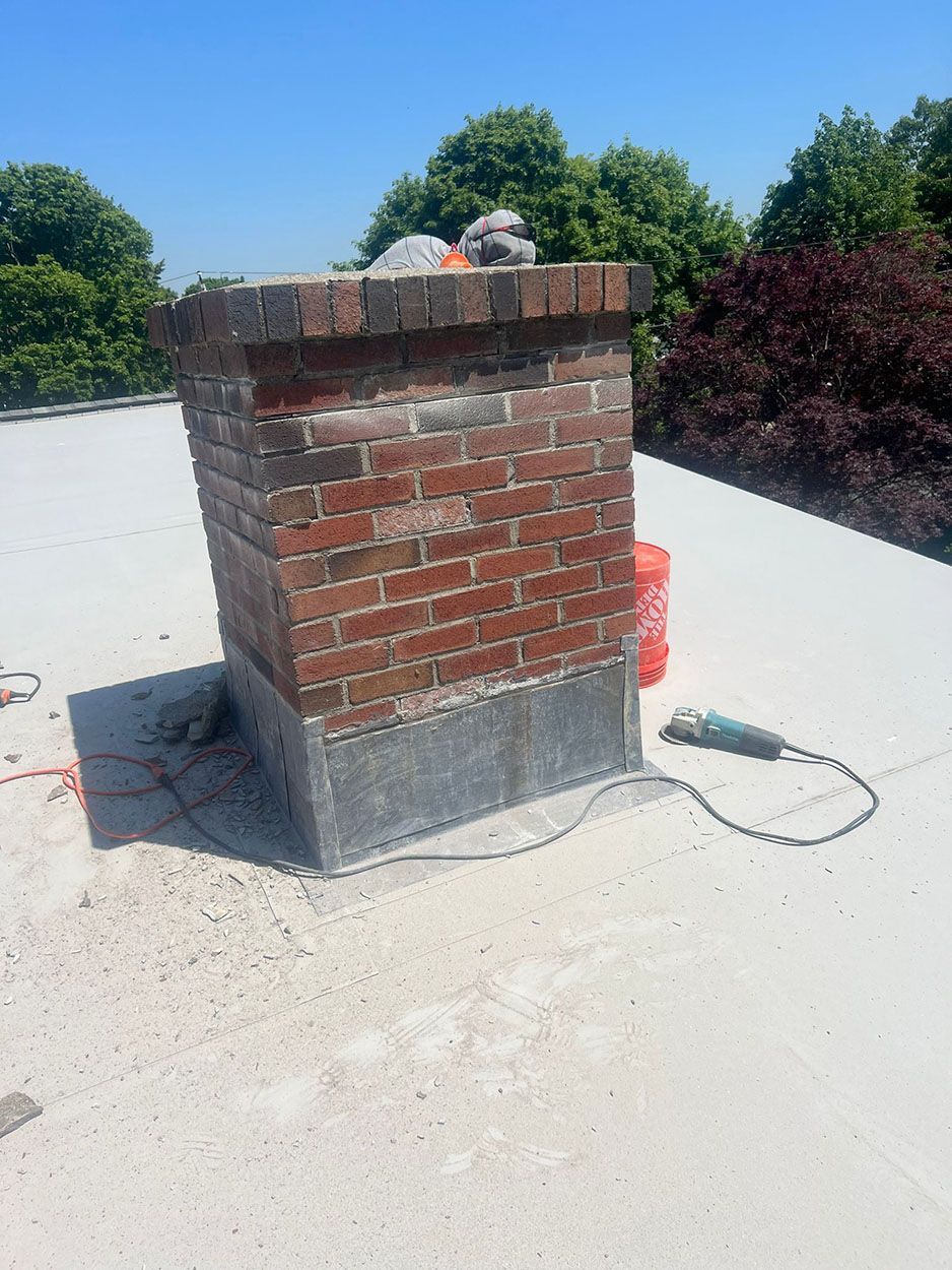 A brick chimney is sitting on top of a white roof