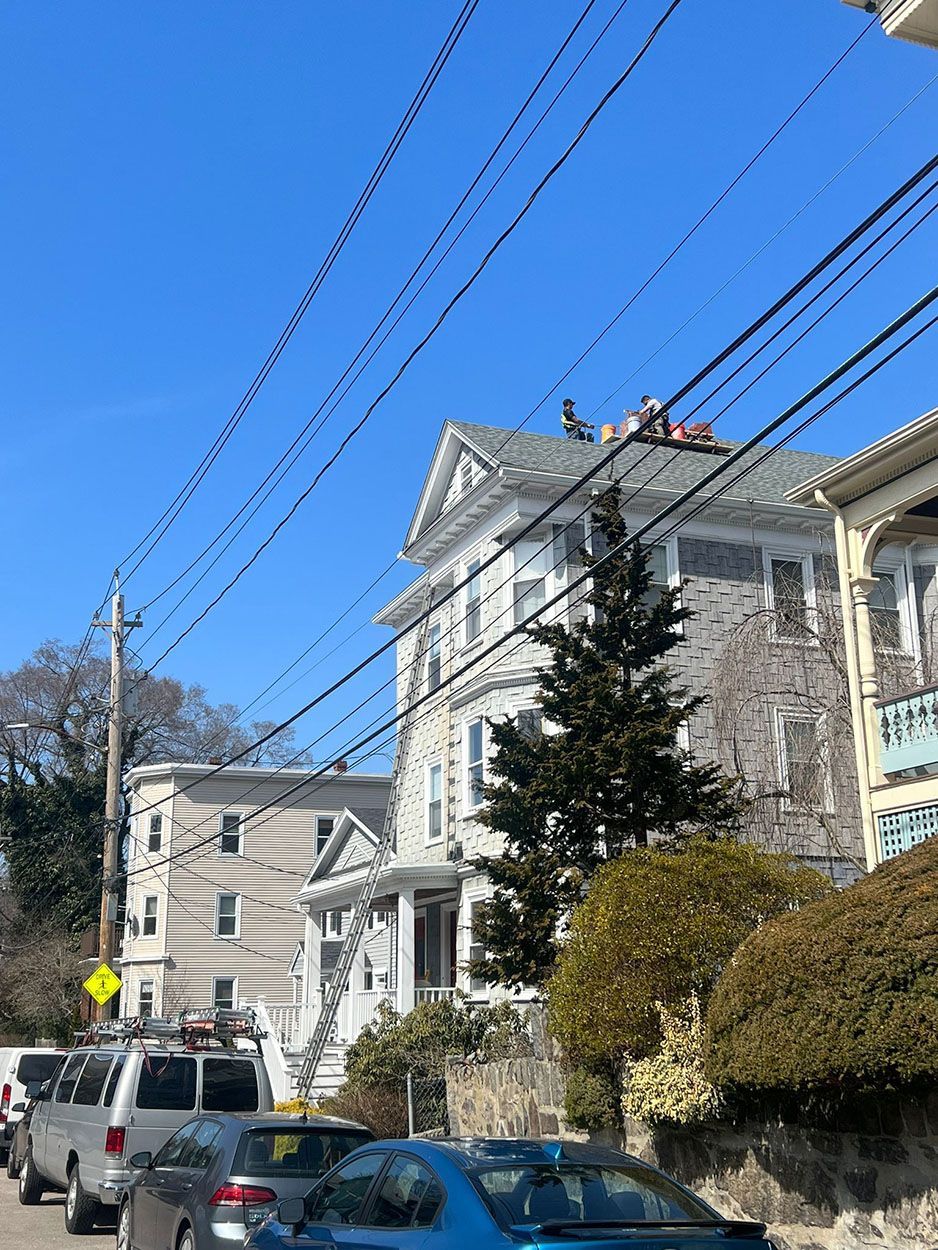 Men working on a chimney on top of the roof of a large house
