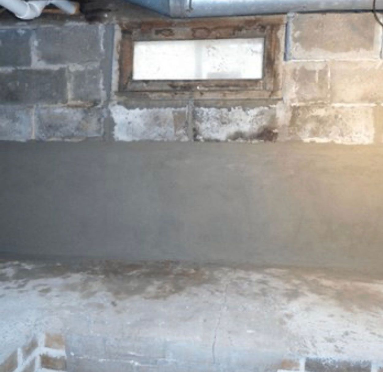 A brick wall with a window in it and a concrete floor