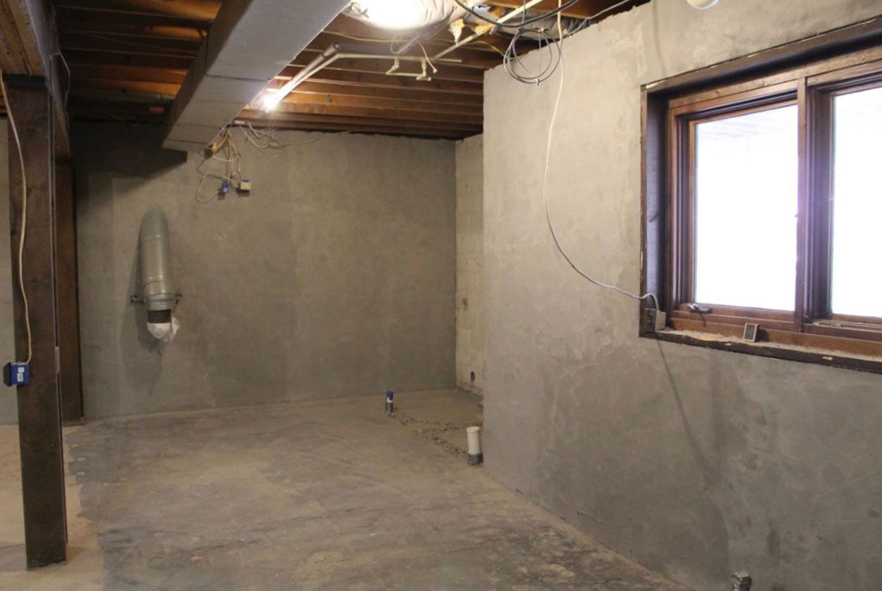 An empty basement with a window and a ceiling fan