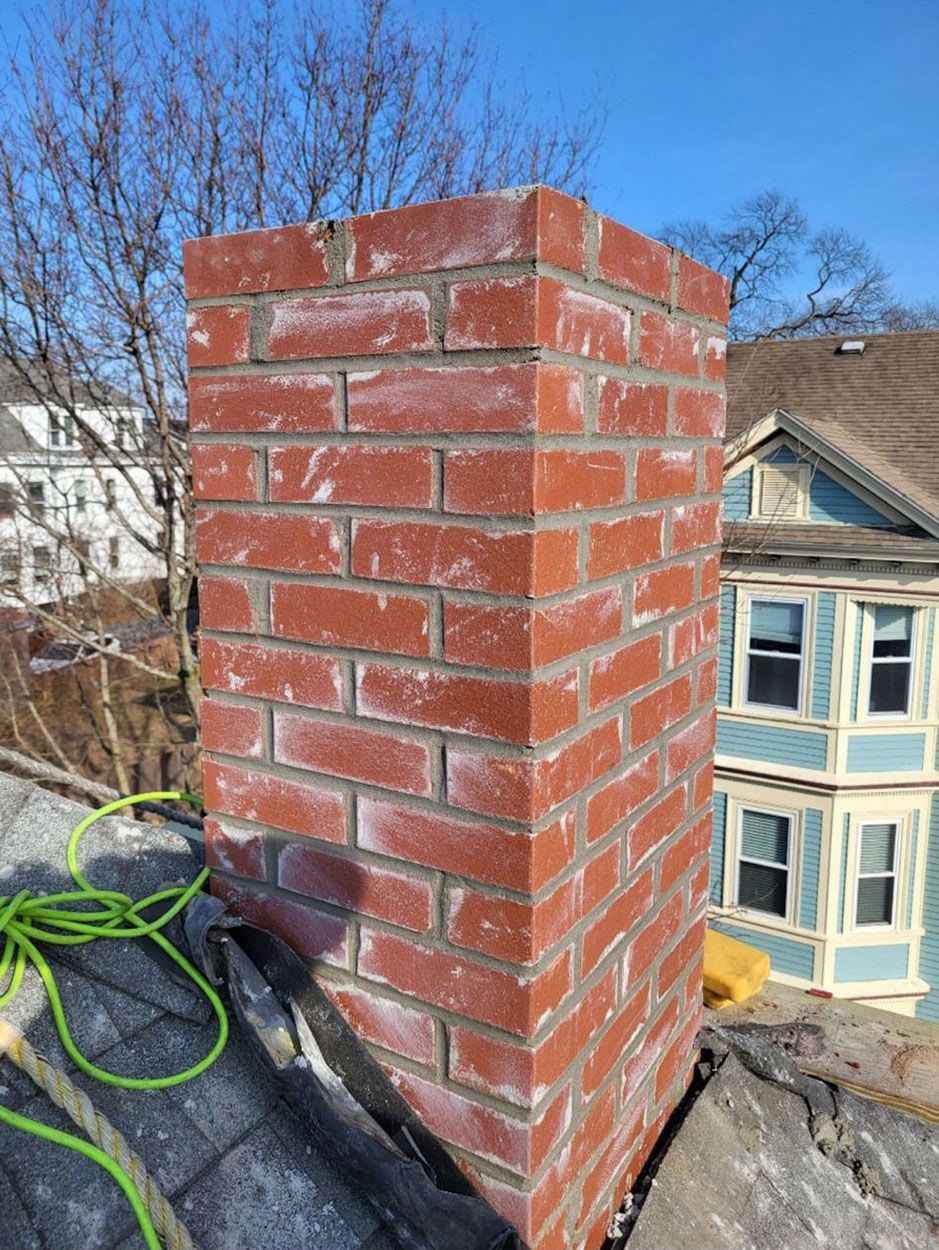 A brick chimney is sitting on top of a roof