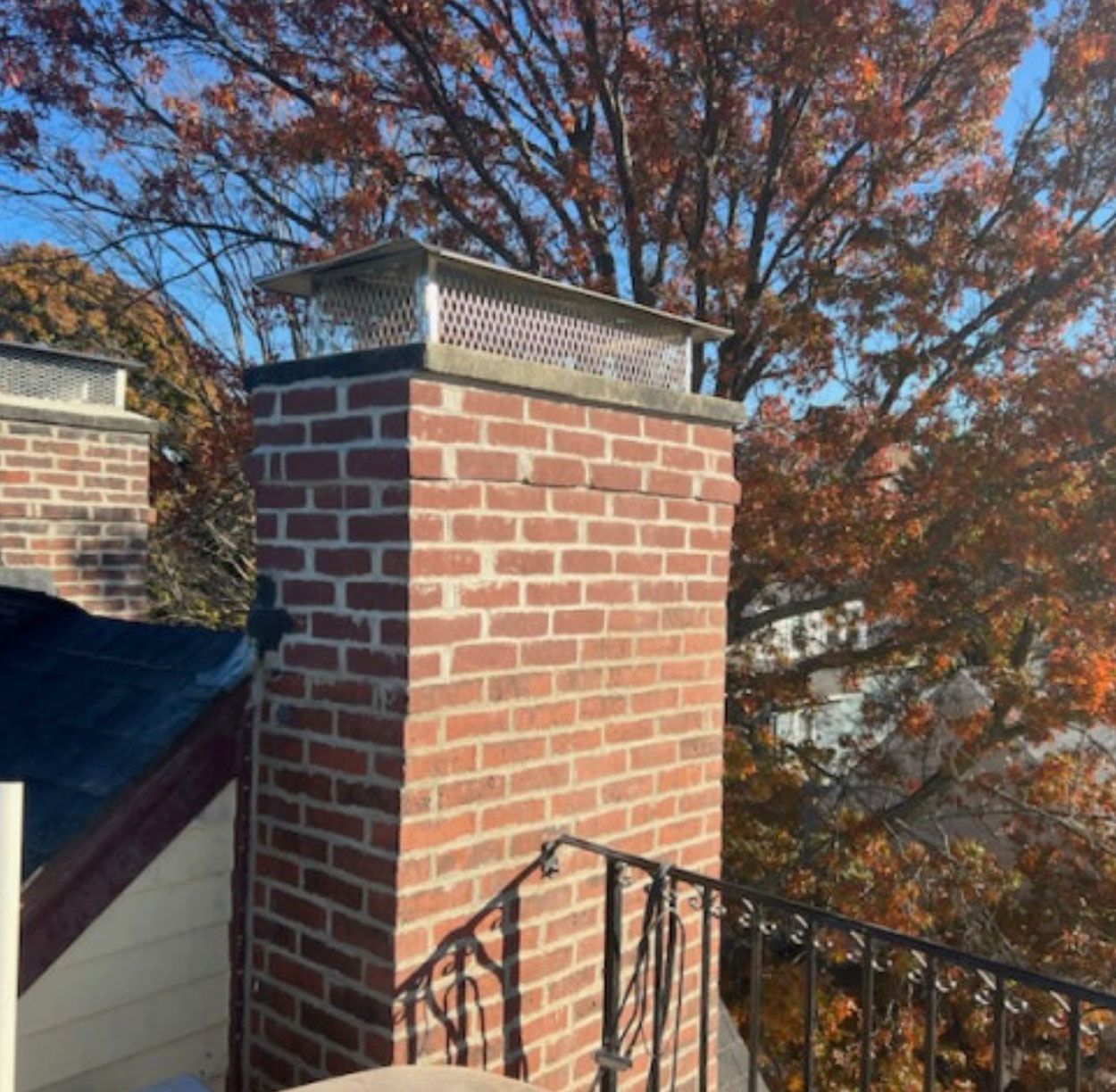 A brick chimney on top of a house with trees in the background