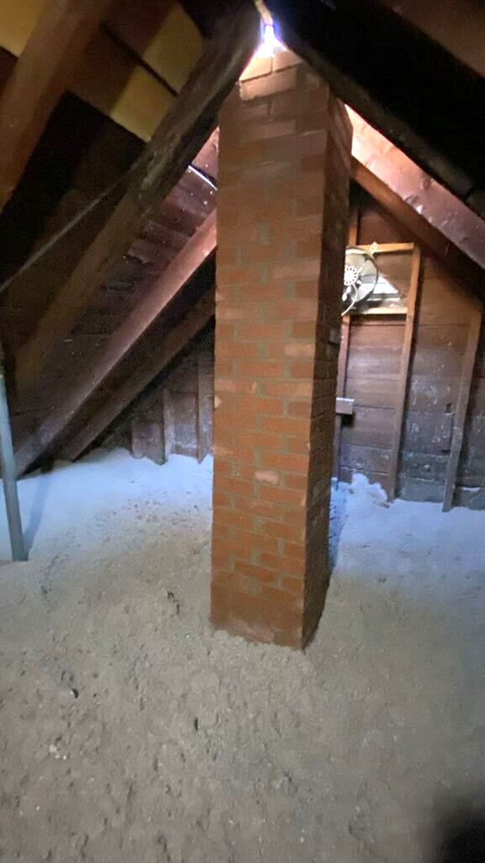 There is a brick chimney in the attic of a house