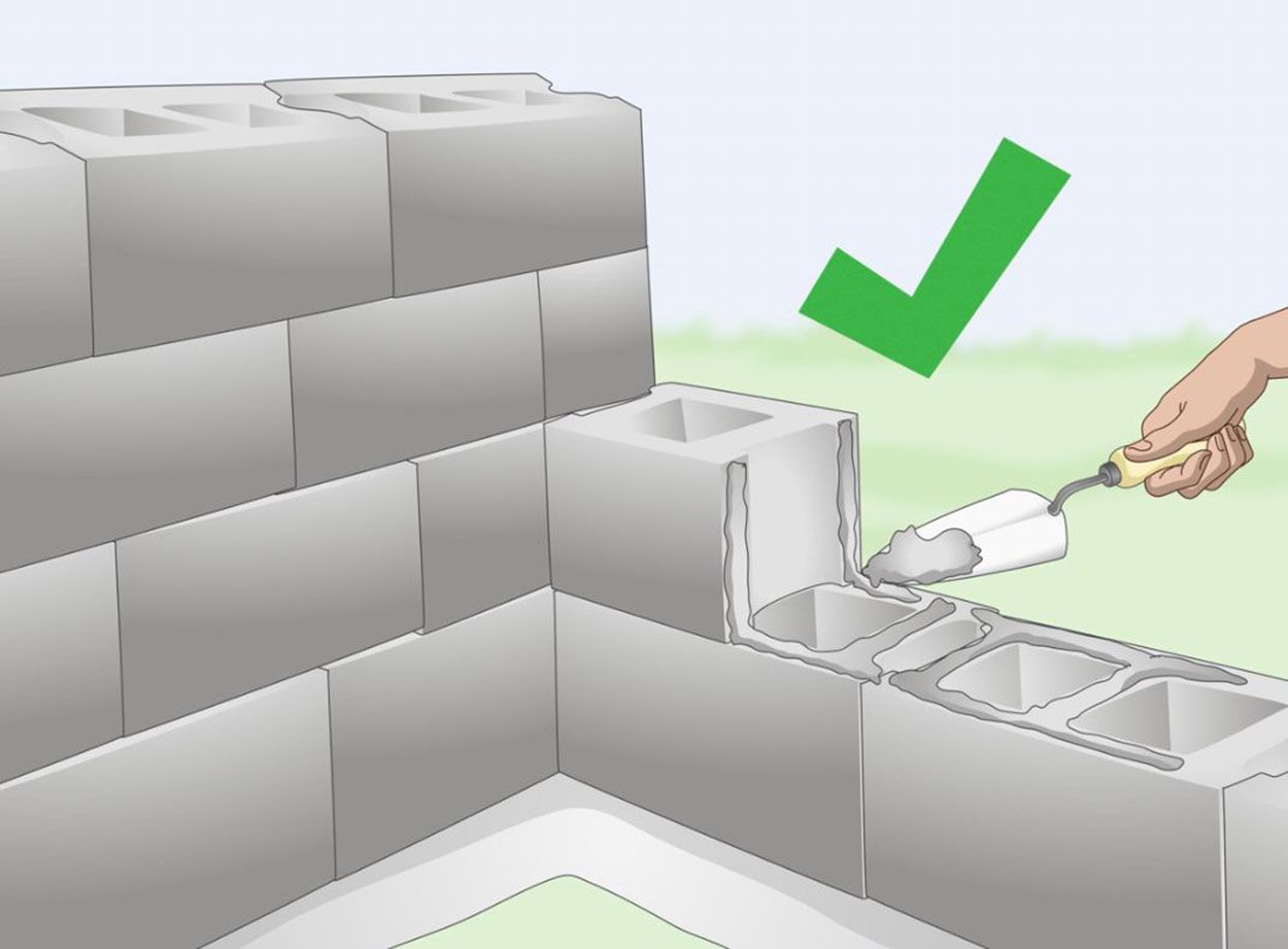 A person is using a trowel to build a brick wall