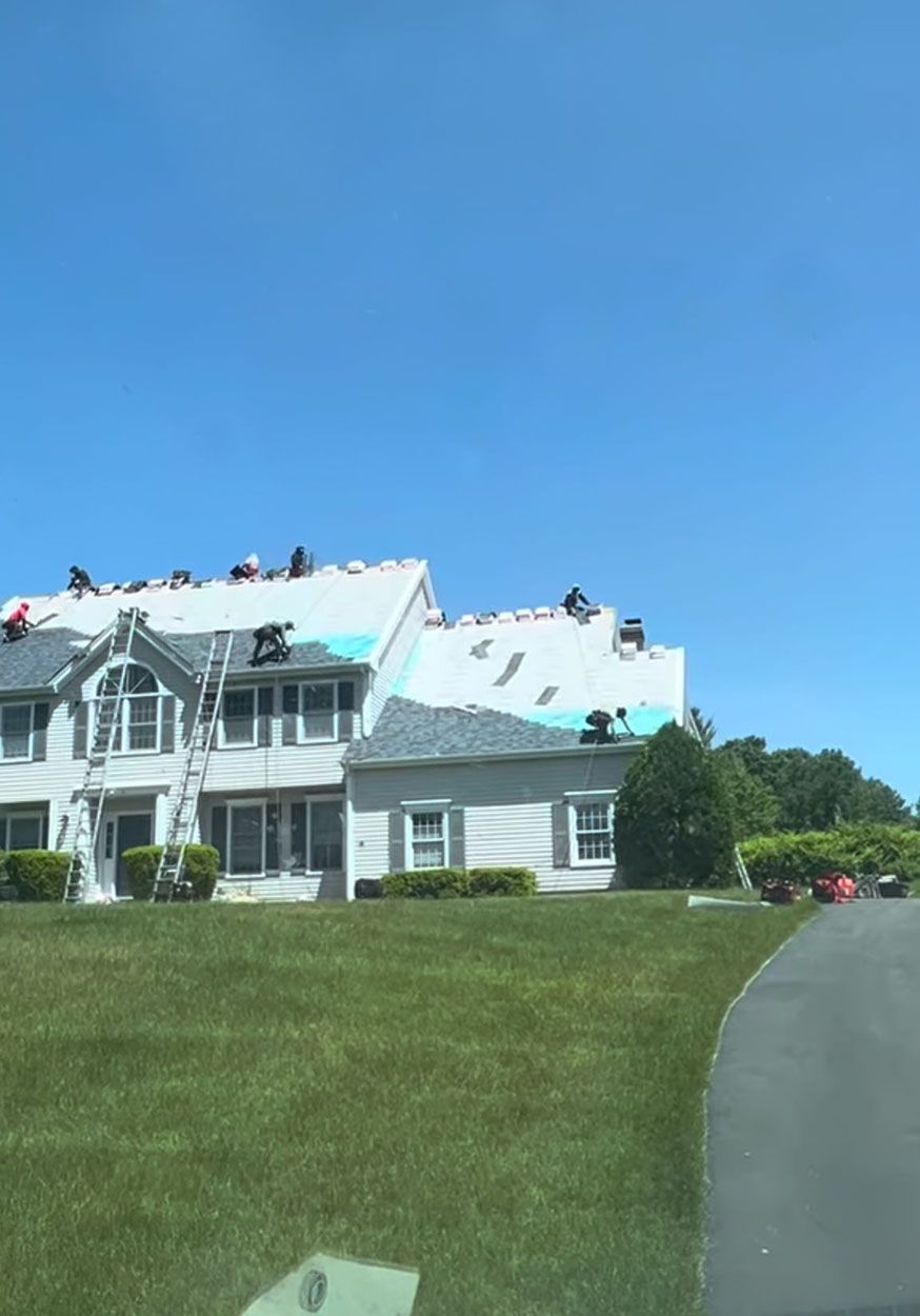 A large white house is being remodeled with a new roof