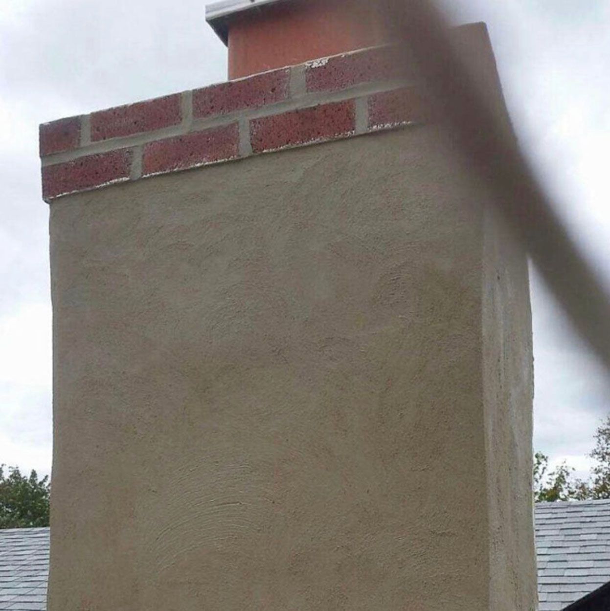 A chimney with a brick border on top of a roof