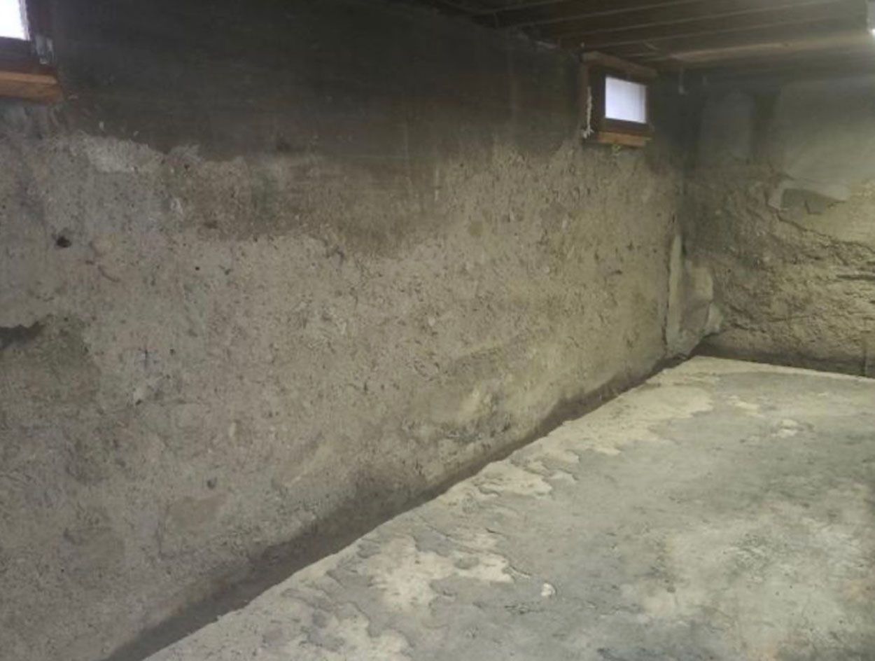 An old empty basement with a concrete floor and a concrete wall