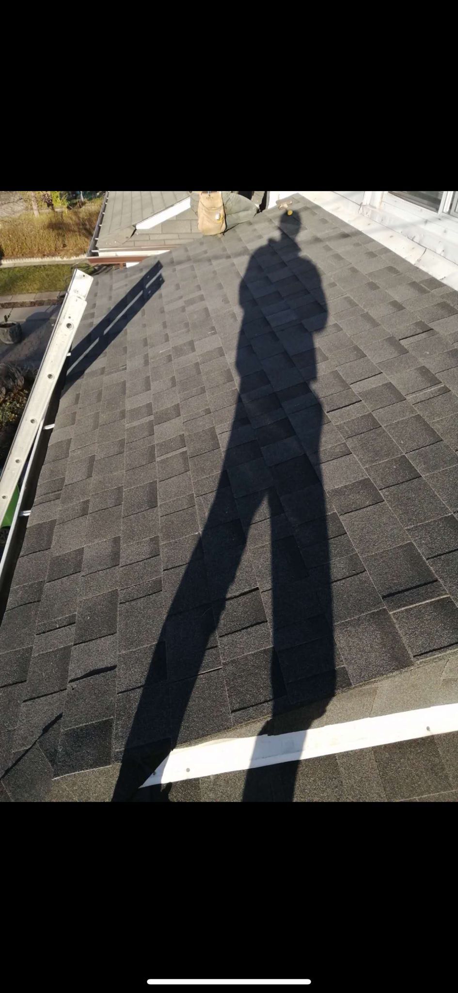 A shadow of a person standing on top of a roof.