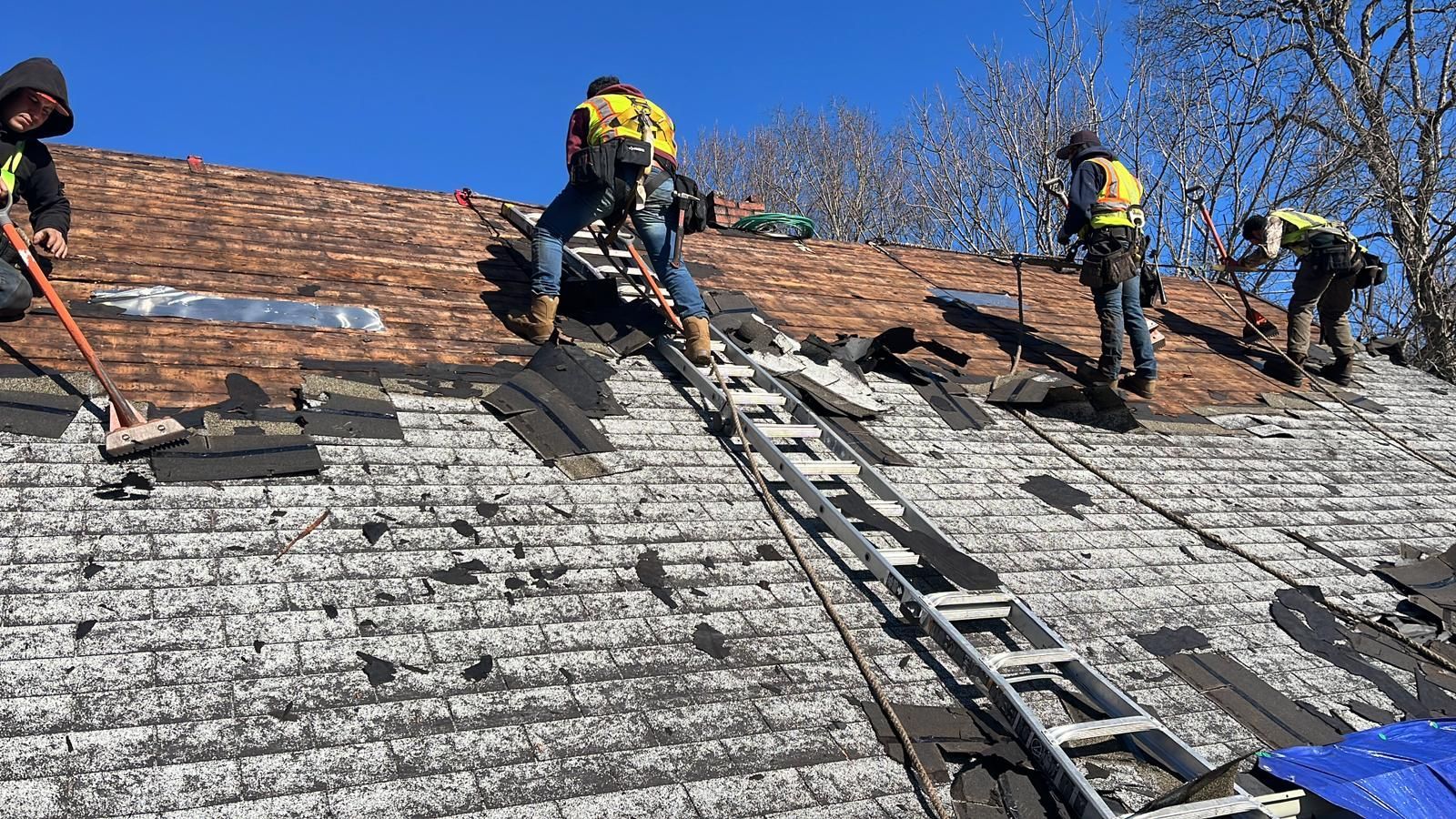 A group of men are working on the roof of a house.