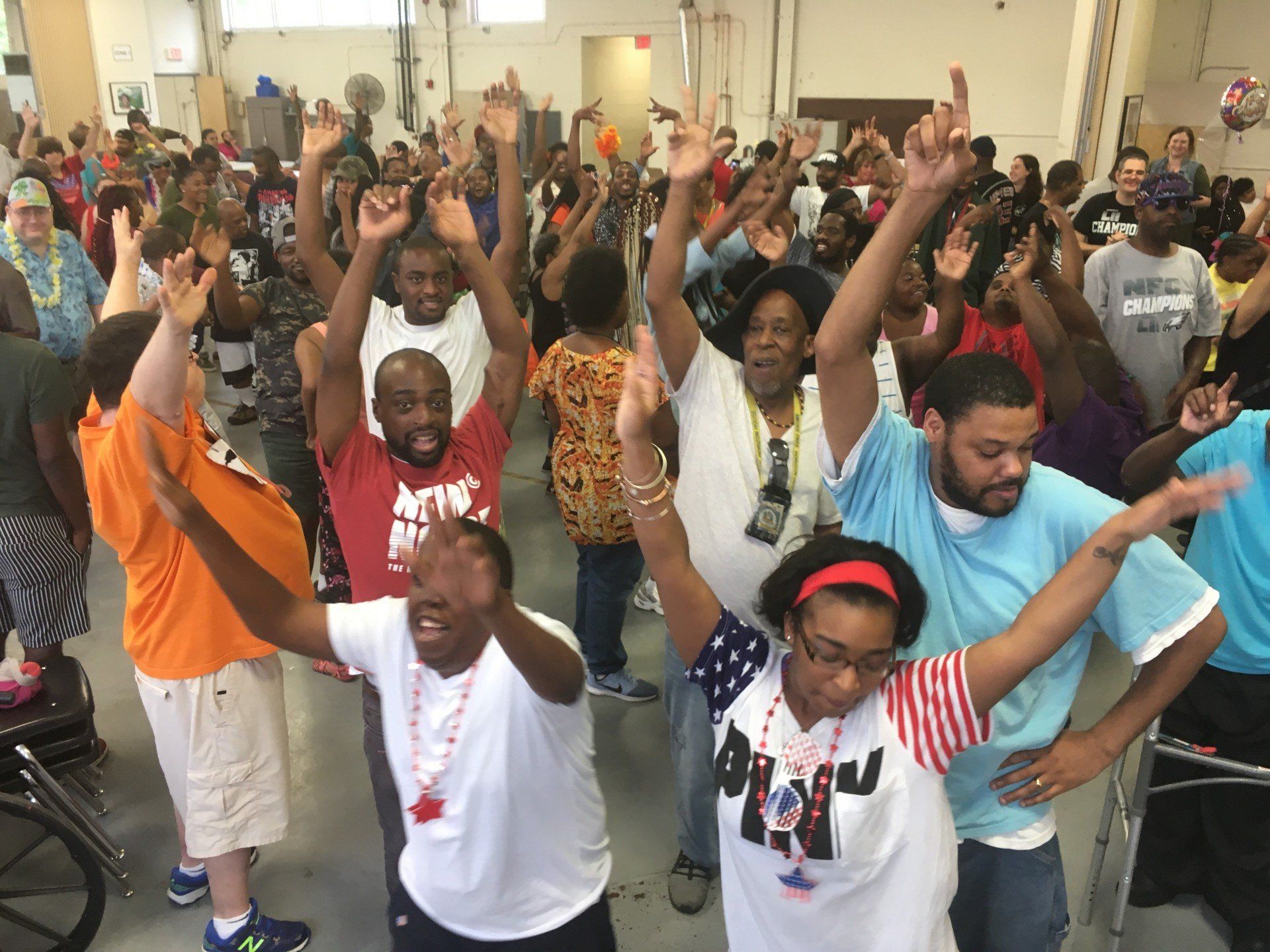 A group of people are standing in a room with their arms in the air.