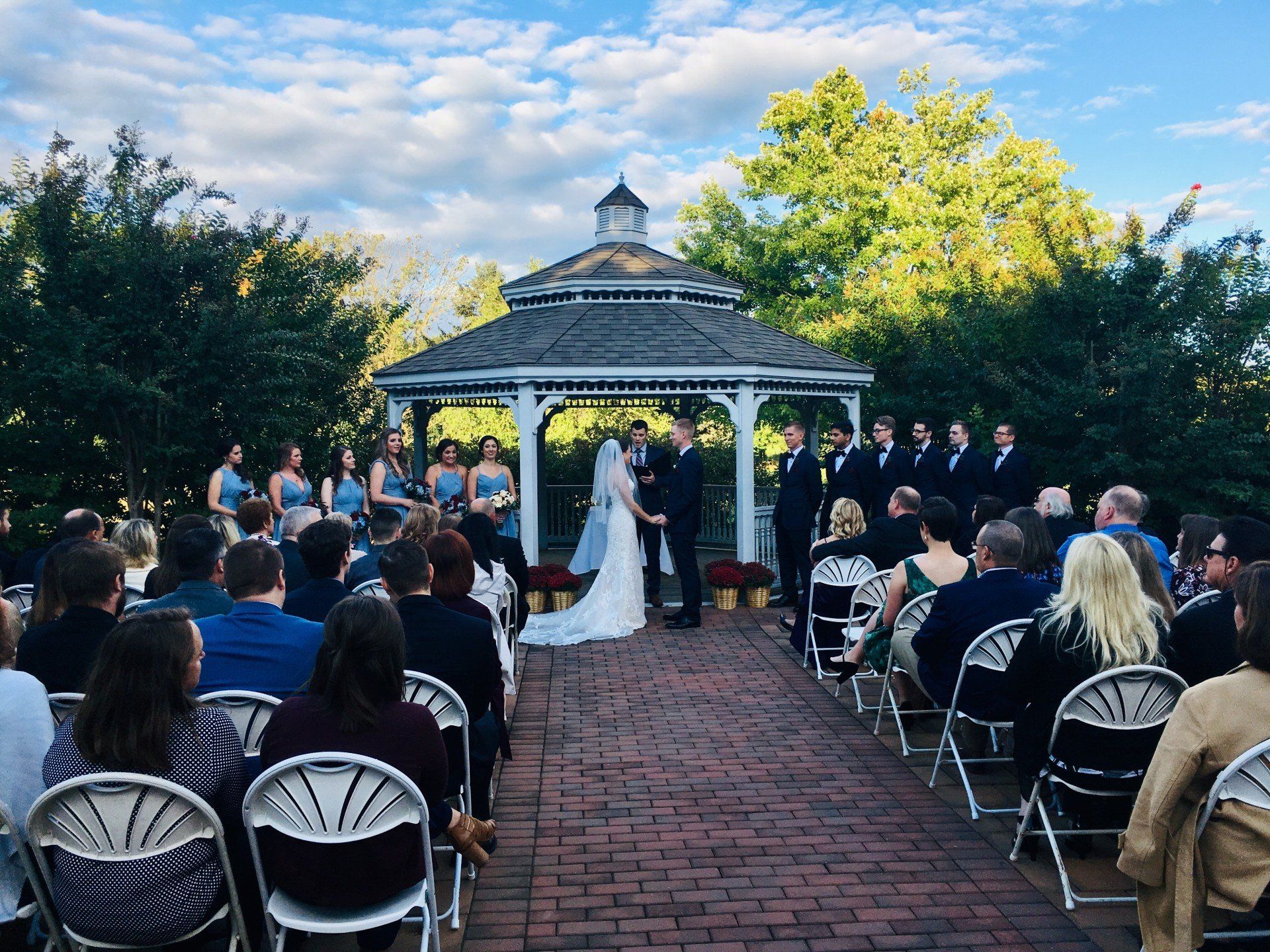 A bride and groom are getting married in front of a crowd of people in a gazebo.