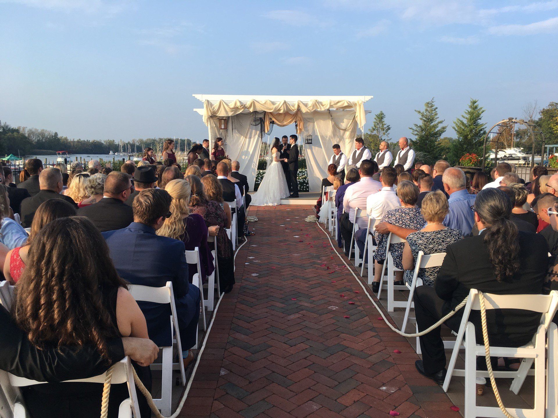 A large group of people are sitting in chairs watching a wedding ceremony.