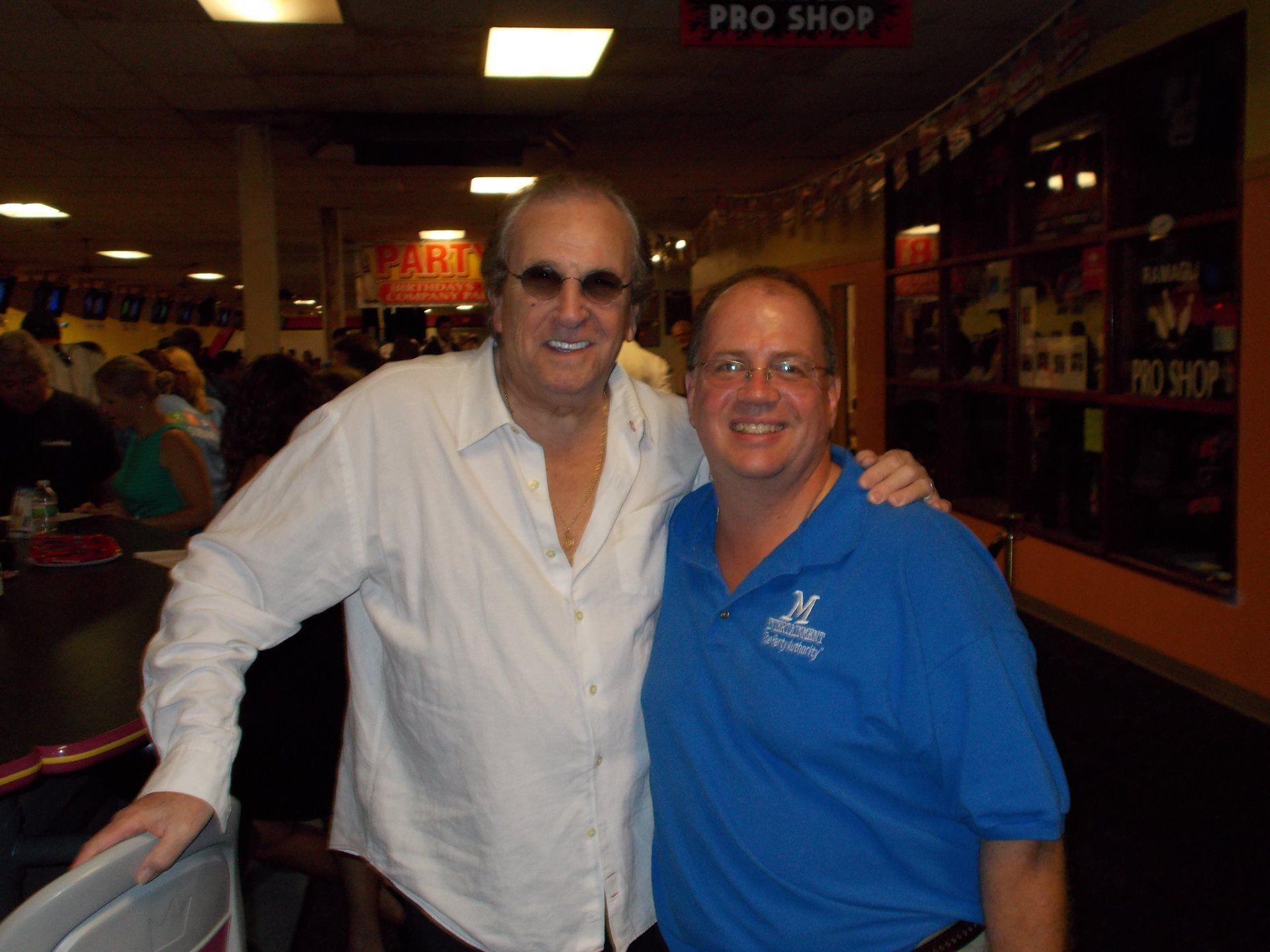 Two men posing for a picture in front of a pro shop sign