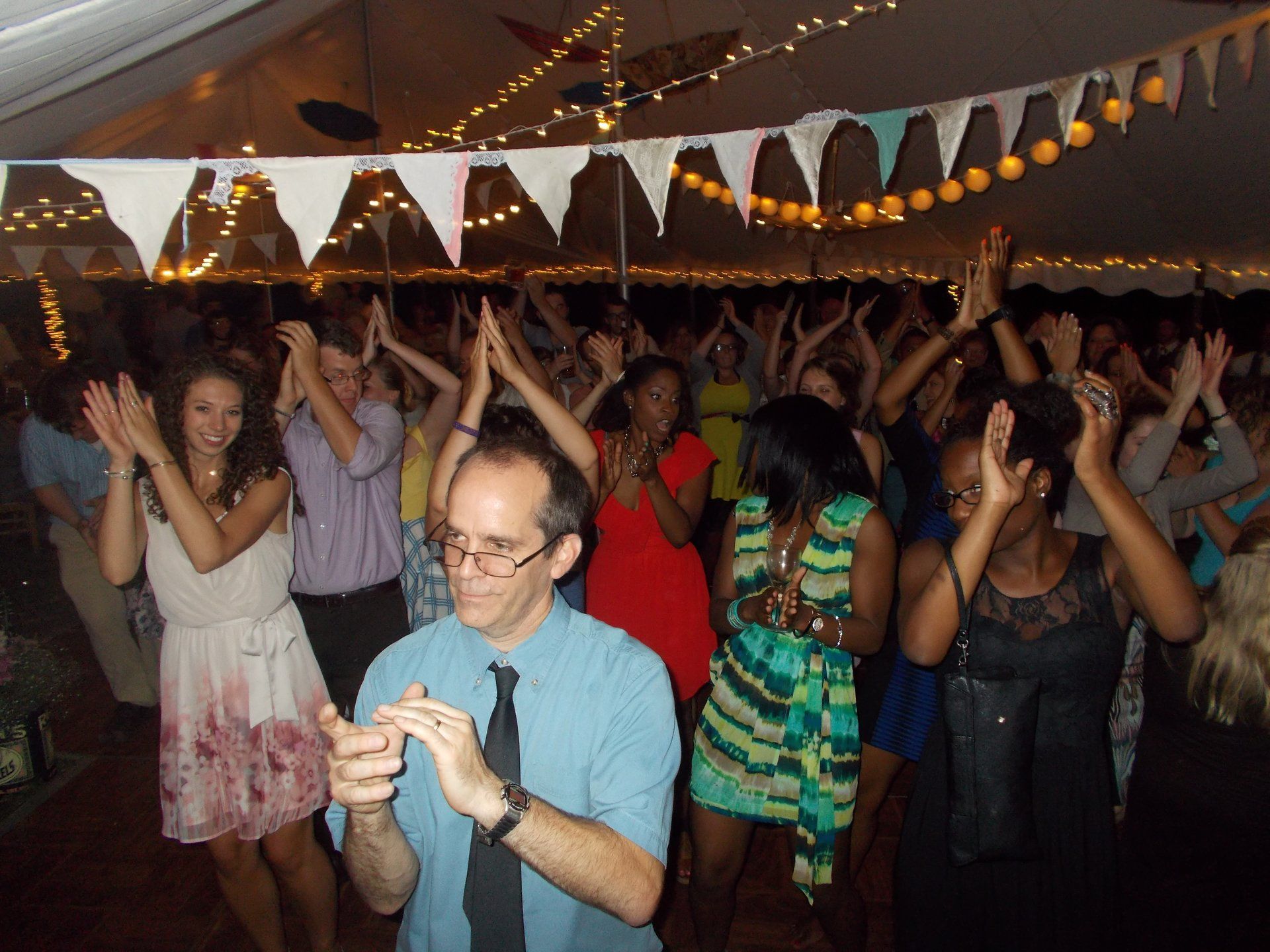 A group of people are dancing in a tent with flags hanging from the ceiling