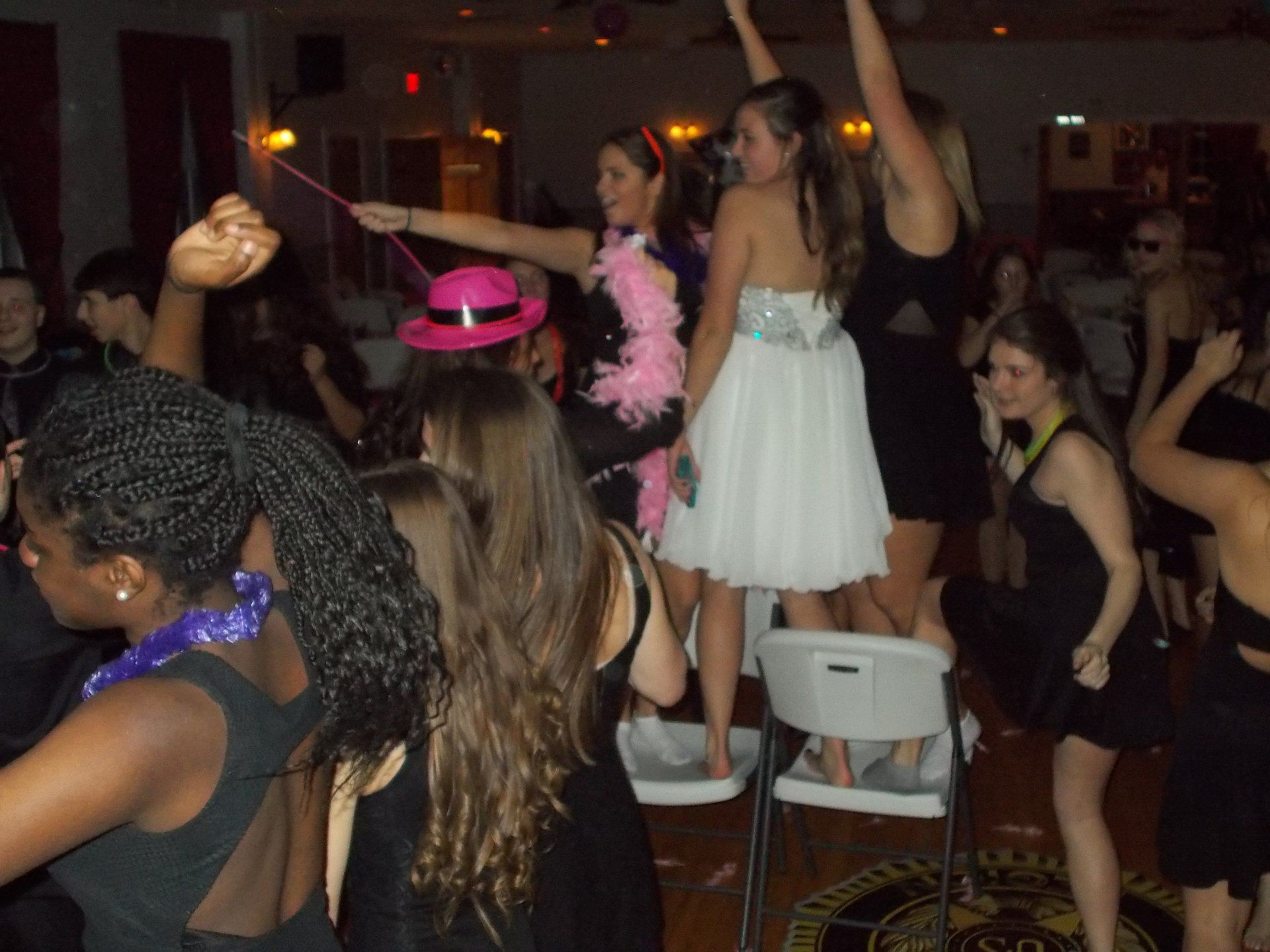 A woman in a white dress is standing on a chair at a party