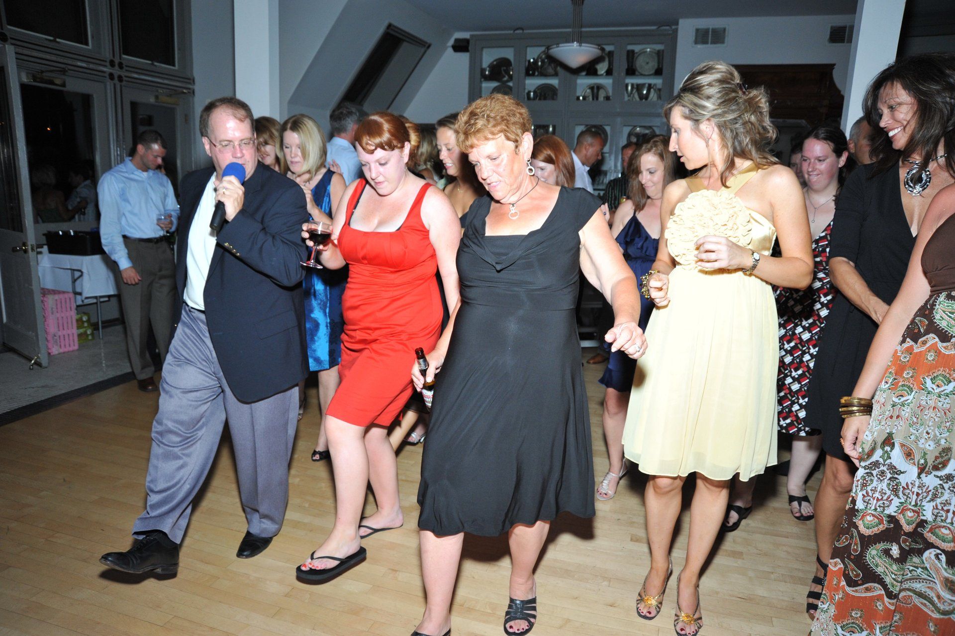 A group of people are dancing in a room with a man singing into a microphone