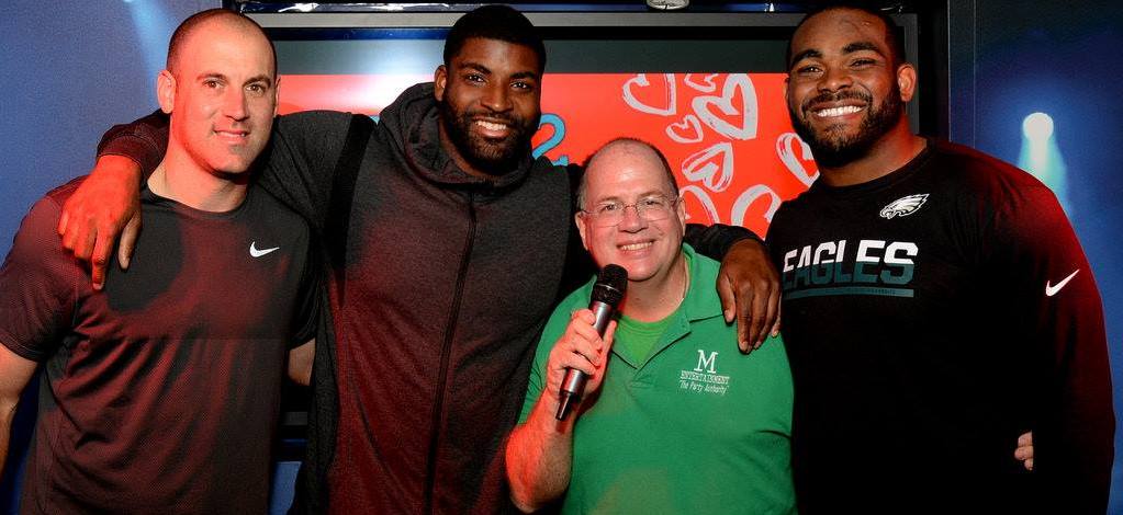 A group of men are posing for a picture with a man holding a microphone.