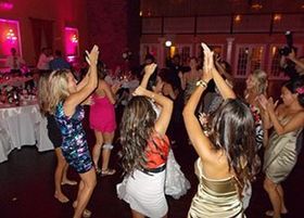 A group of women are dancing in a room at a wedding reception.