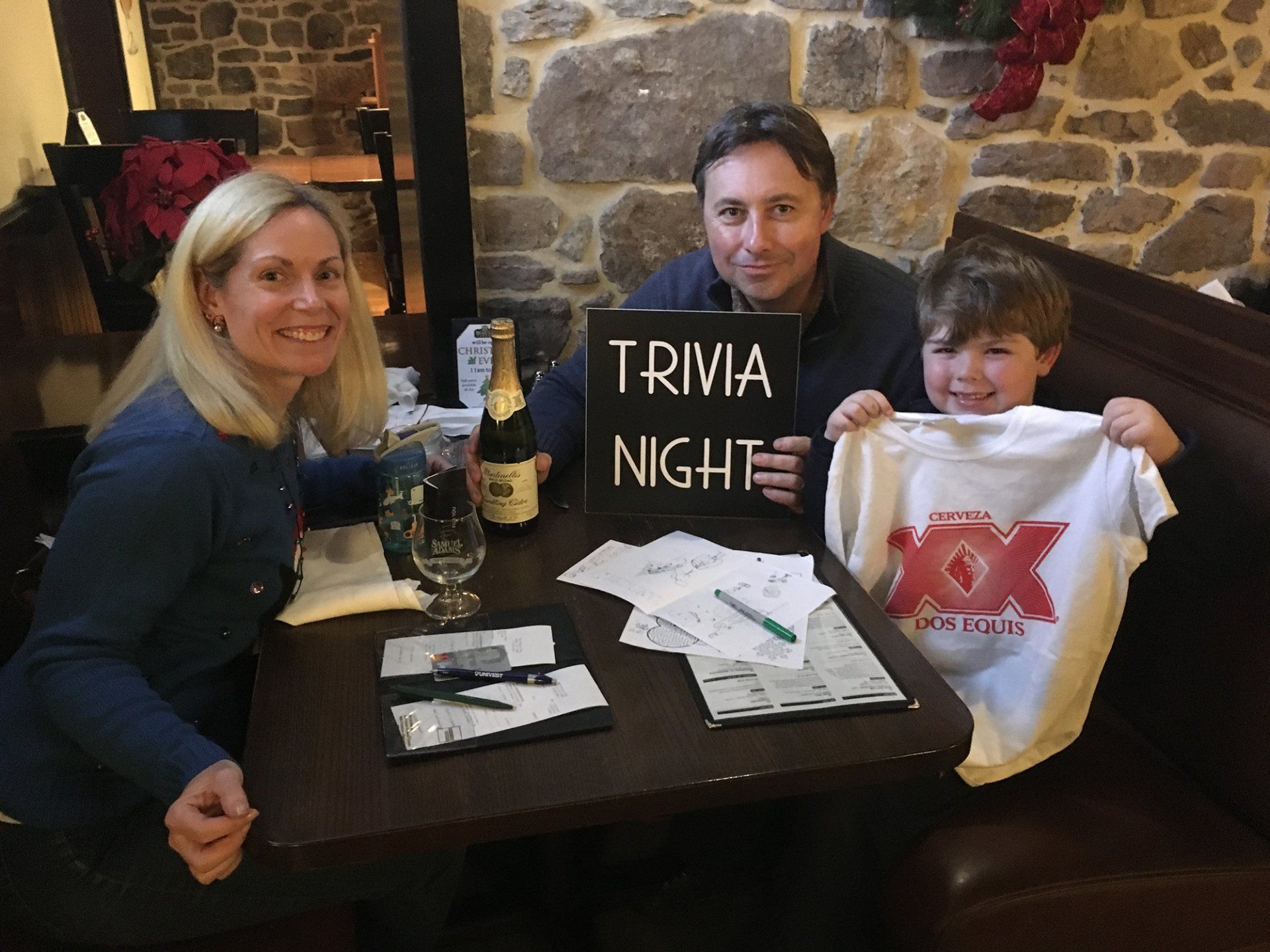 A man and woman are sitting at a table holding a sign that says trivia night
