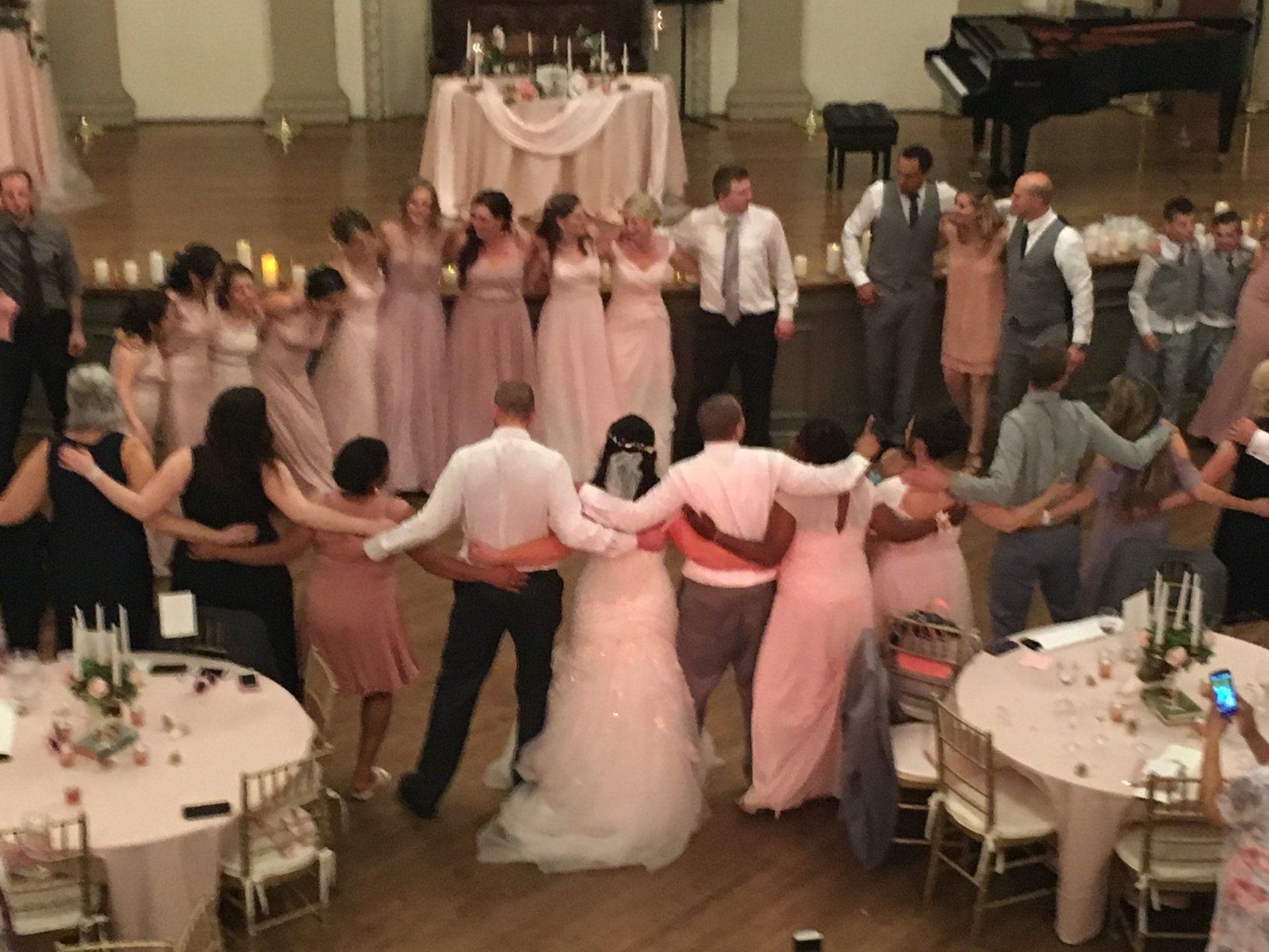 A group of people are dancing in a circle at a wedding reception.