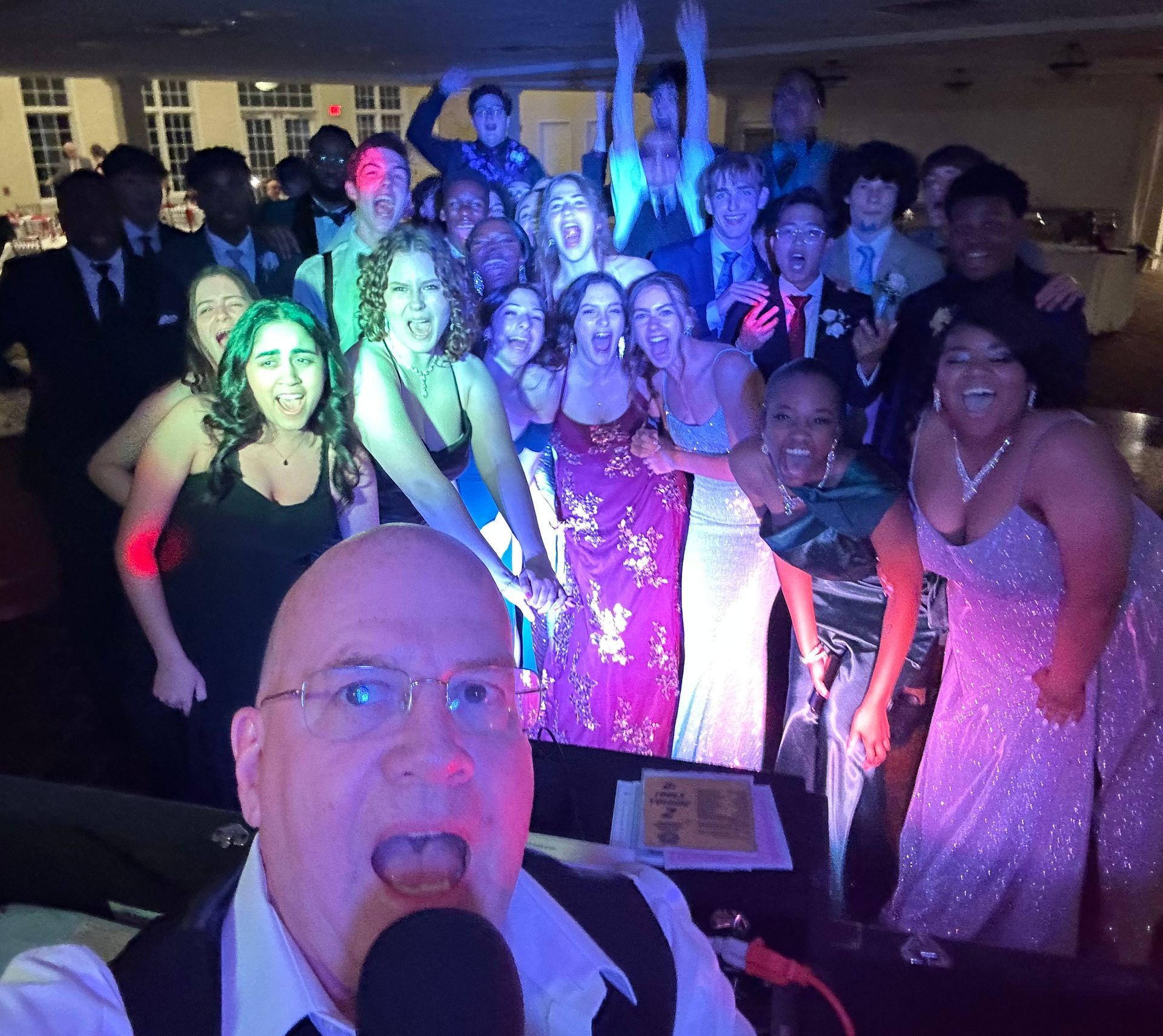 A man is taking a selfie with a microphone in front of a group of people