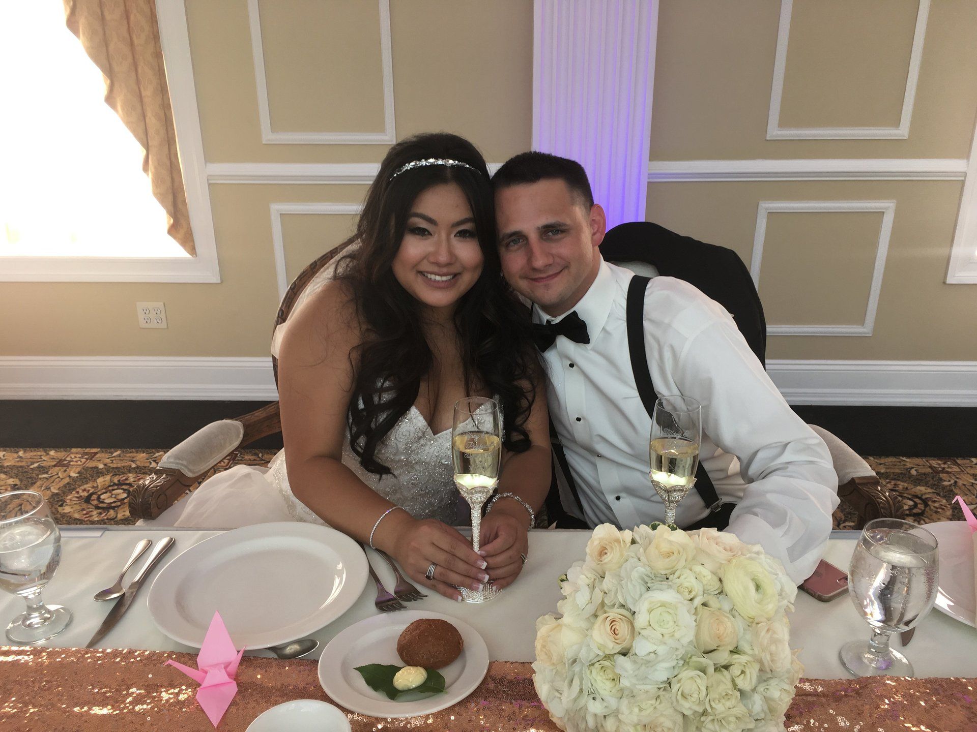 A bride and groom are posing for a picture at their wedding reception.
