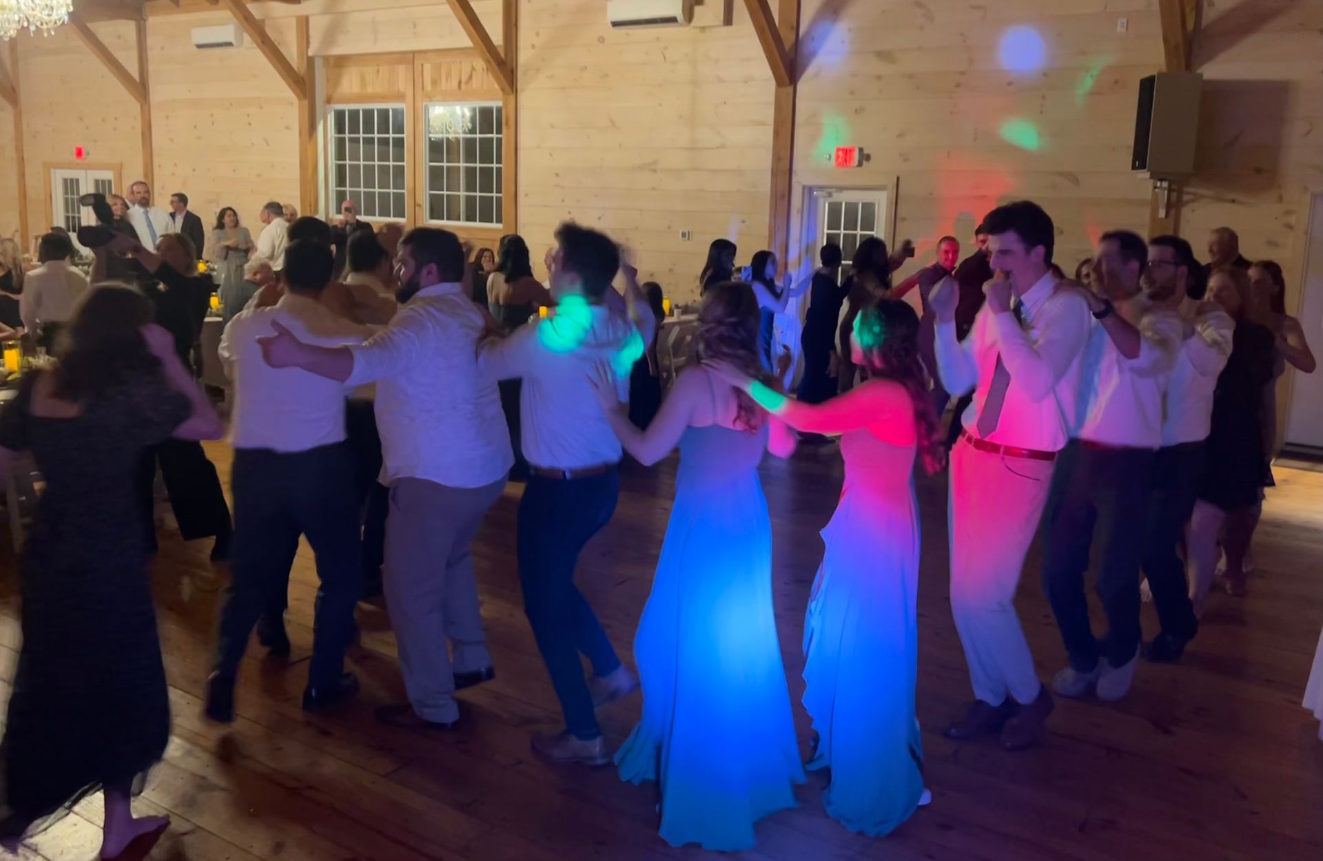 A group of people are dancing on a dance floor at a wedding reception.