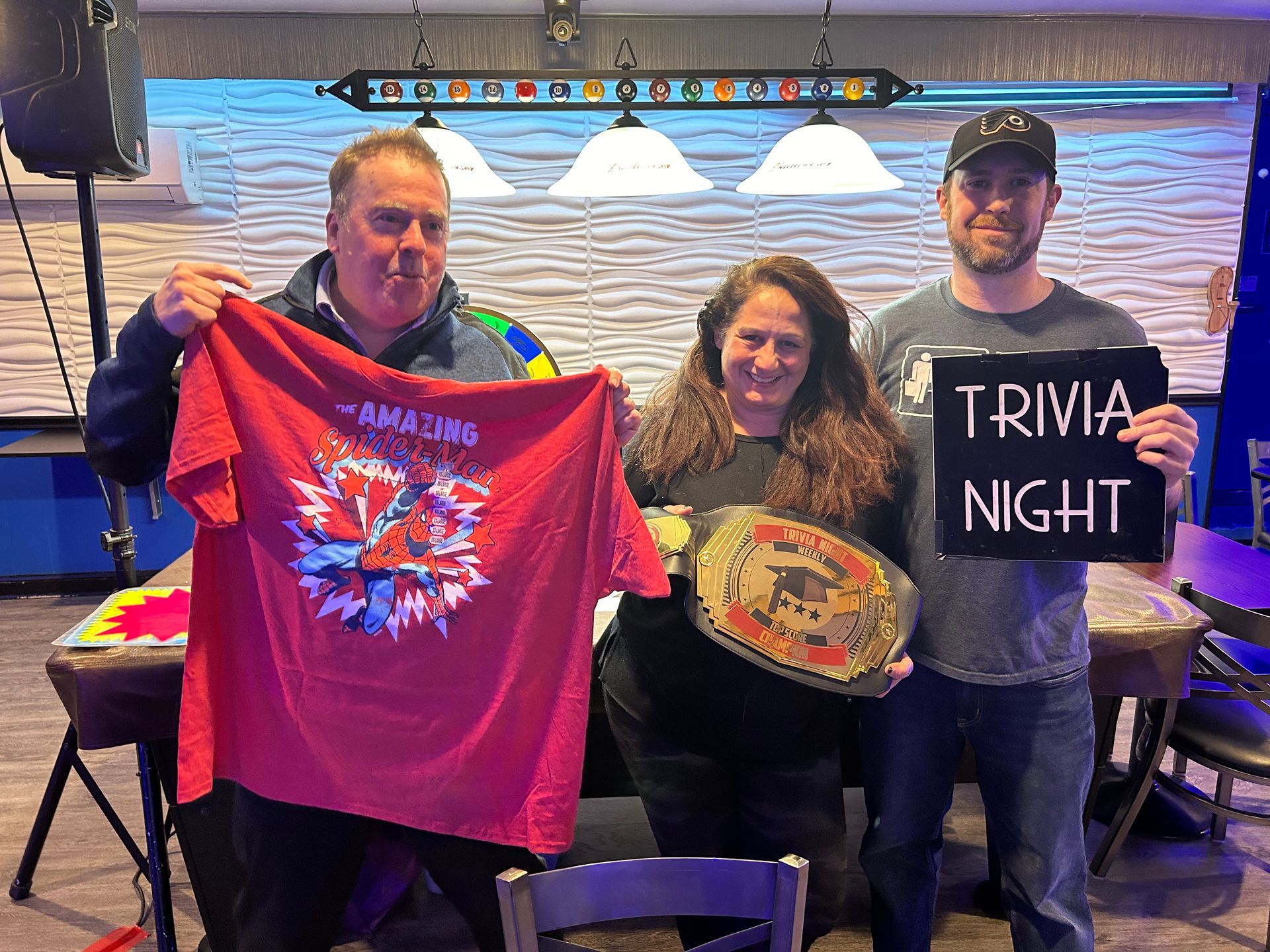 A group of people holding a sign that says trivia night.