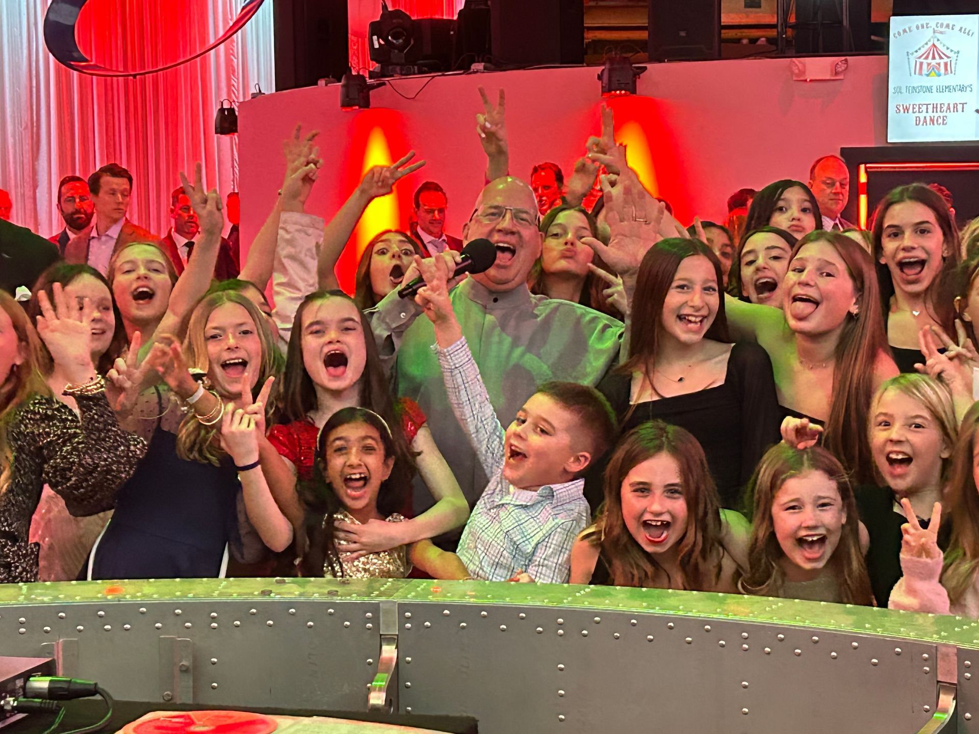 A group of children are posing for a picture with a man holding a microphone.