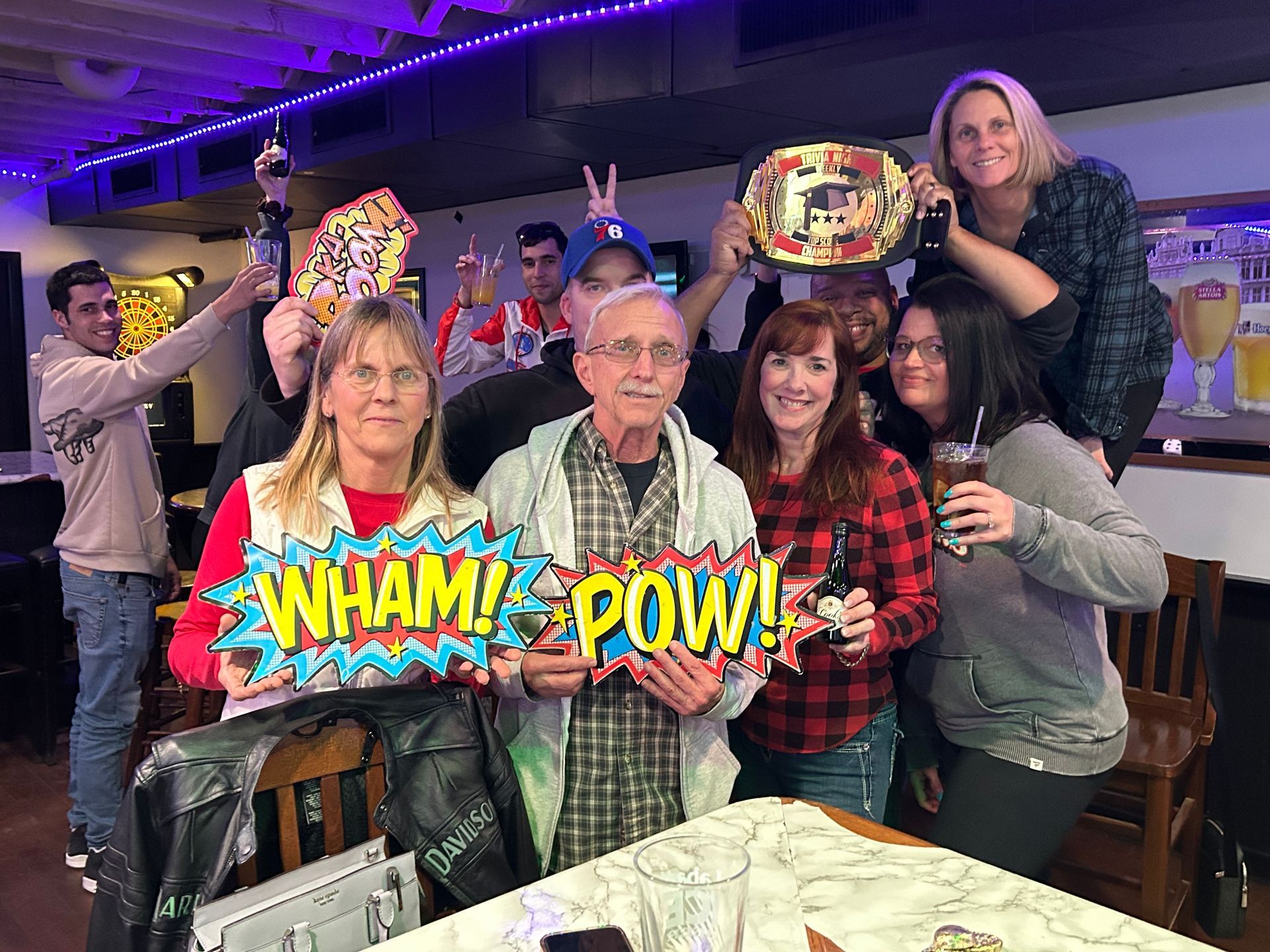 A group of people are standing around a table holding signs that say wham pow.