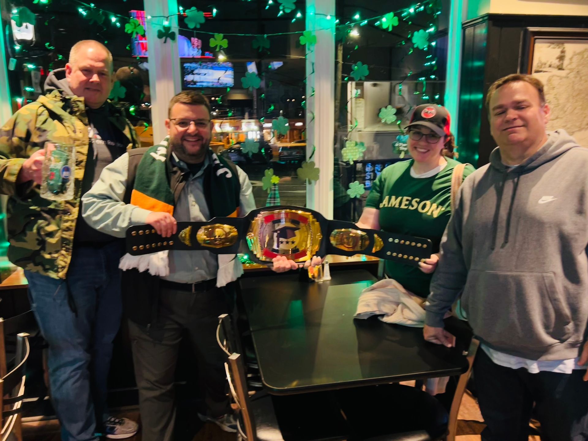 A group of people standing around a table holding a championship belt.
