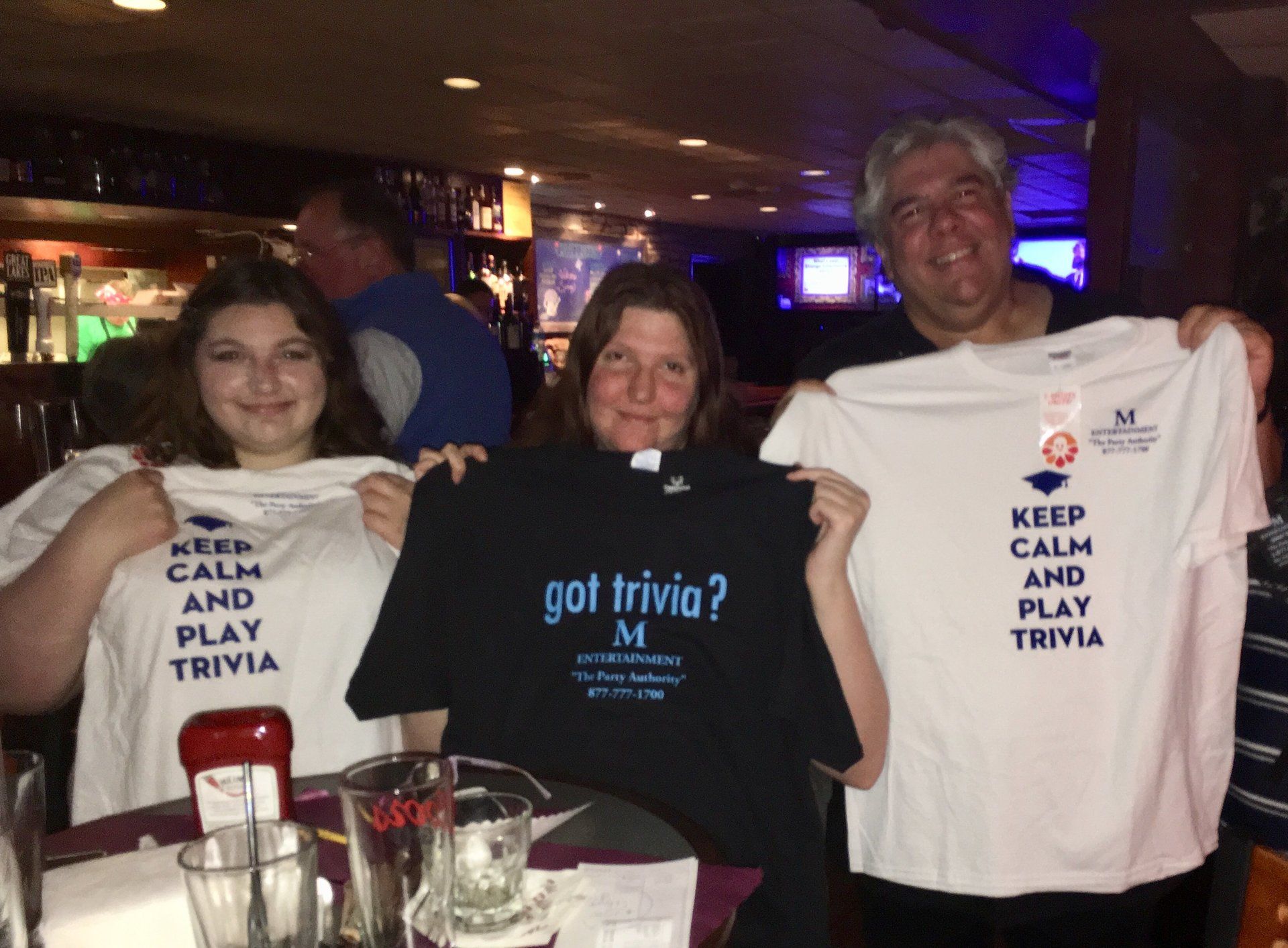 Three people are holding up shirts that say 