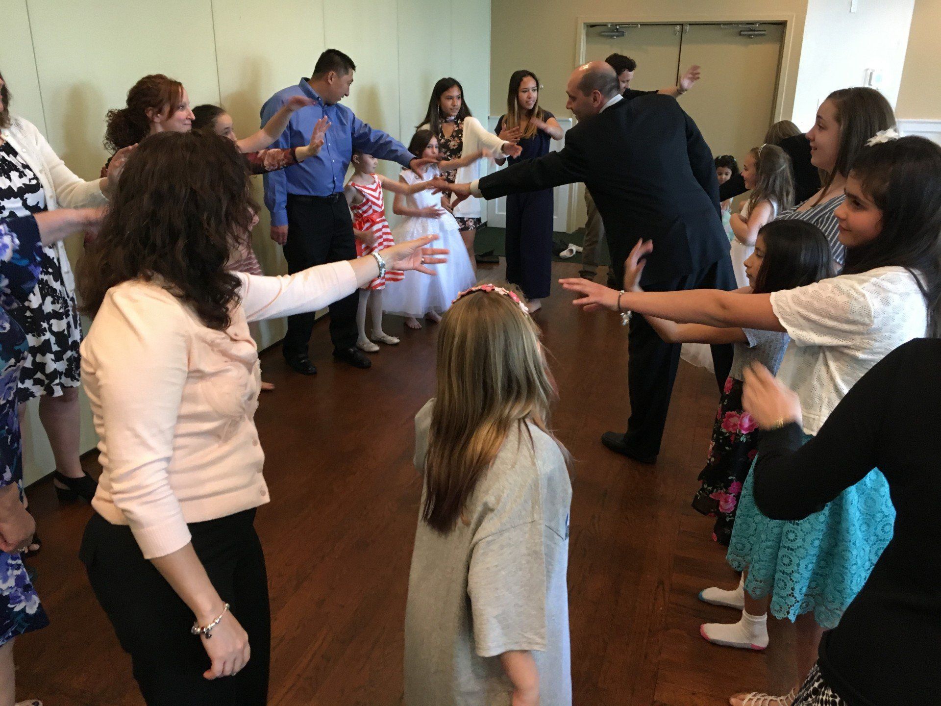 A group of people are dancing in a circle in a room.