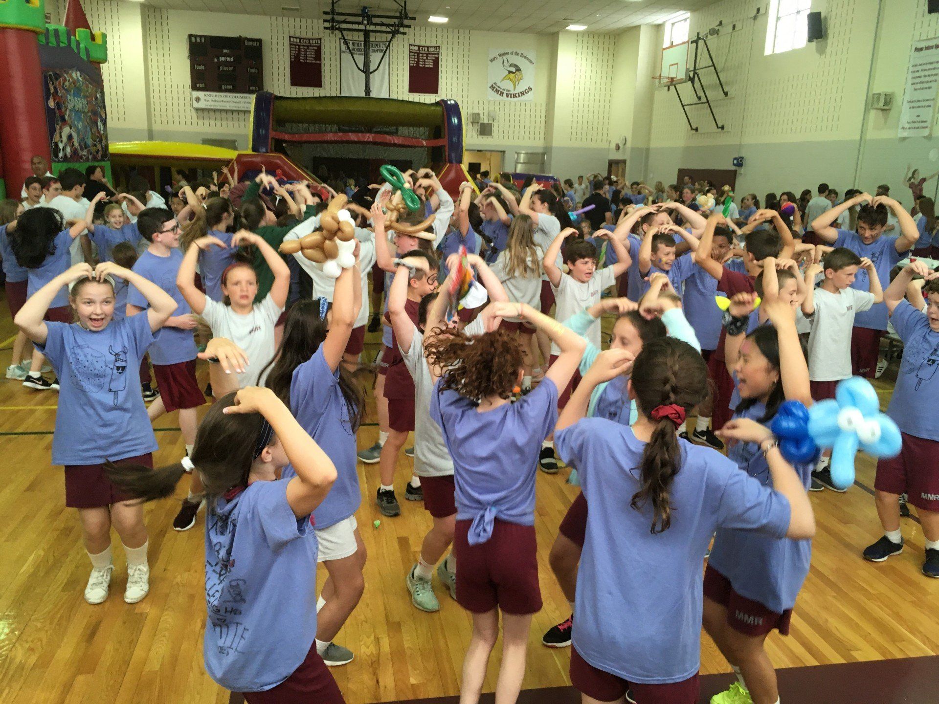 A large group of children are dancing in a gym.