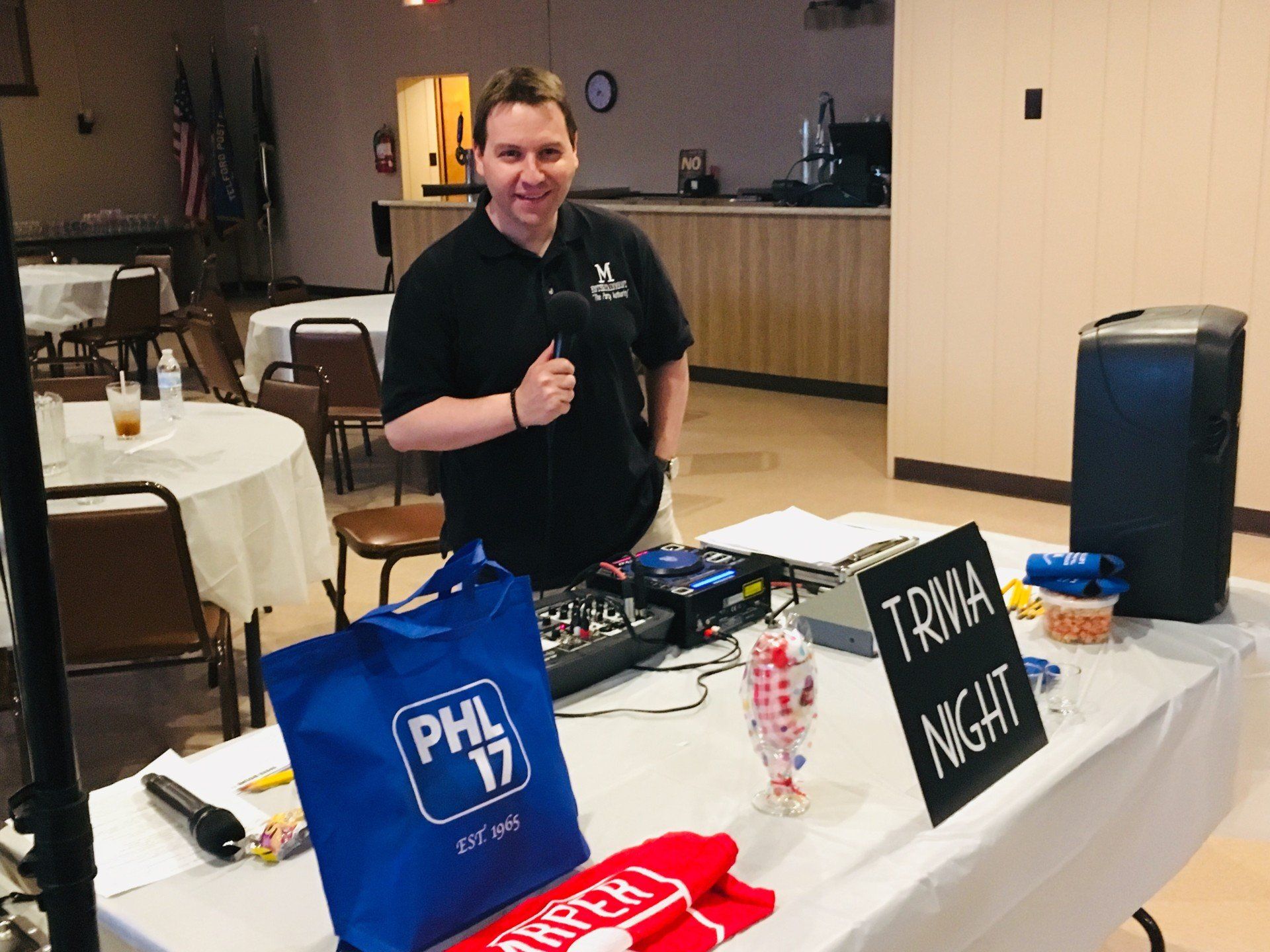A man is standing in front of a table with a sign that says trivia night