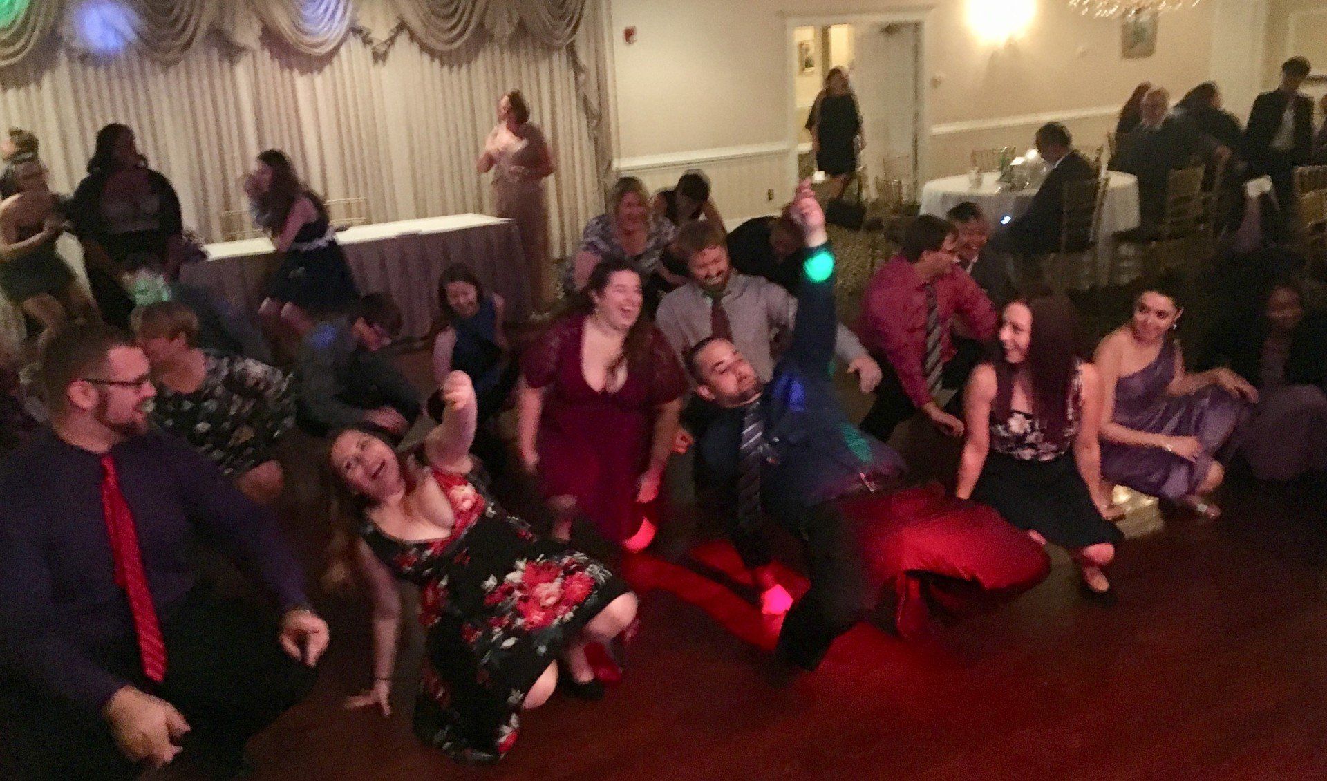 A group of people are dancing in a room at a wedding reception.