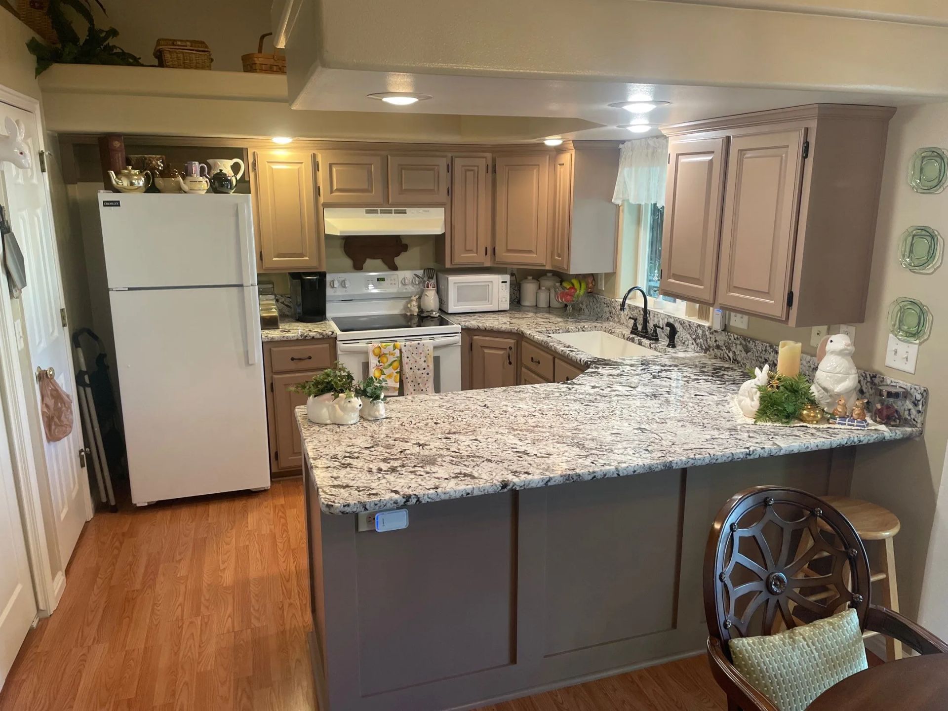 Kitchen with white refrigerator, granite island, wood cabinets, and hardwood floors.