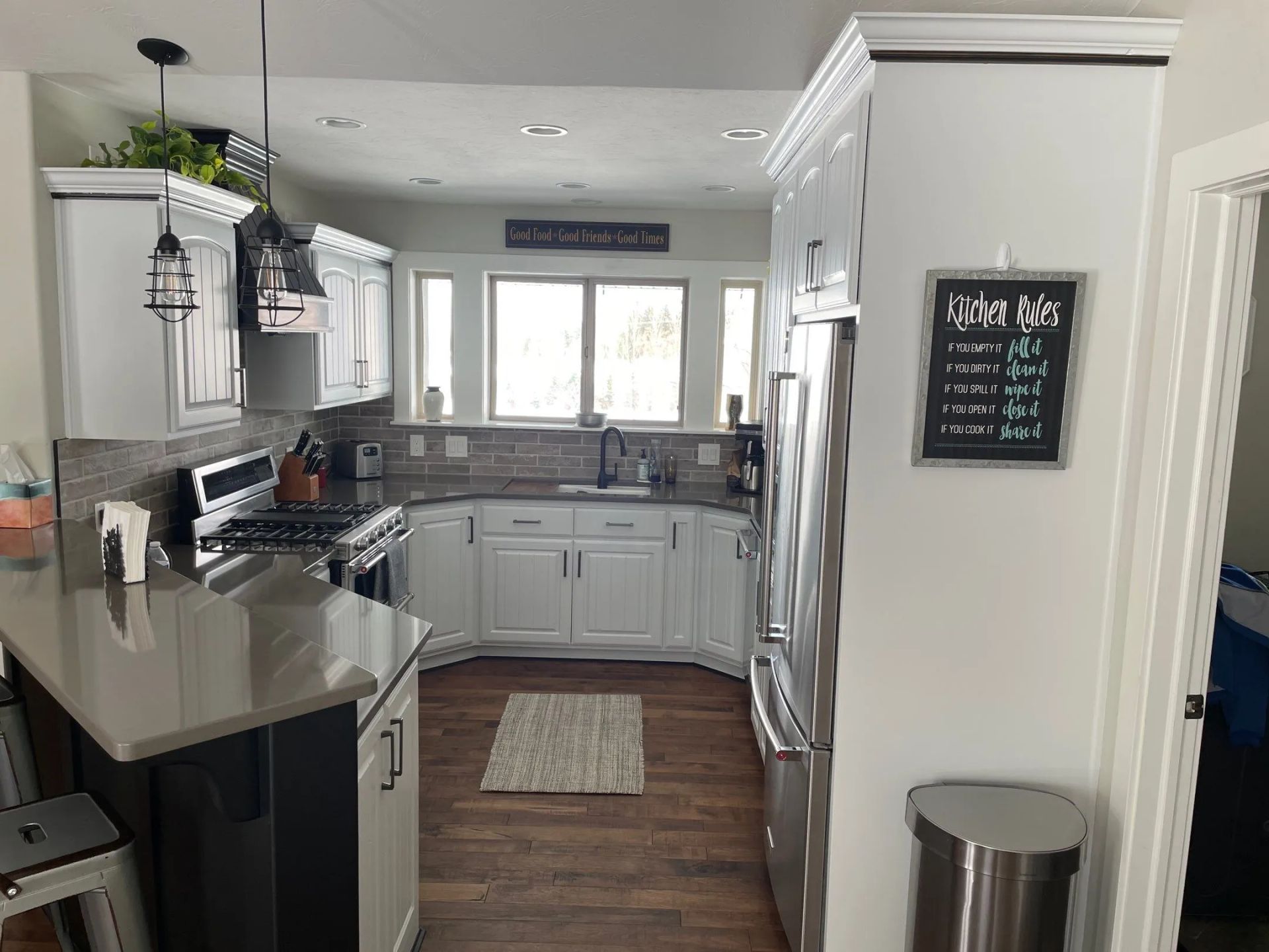 Modern white kitchen with gray counters, stainless appliances, and a window over the sink