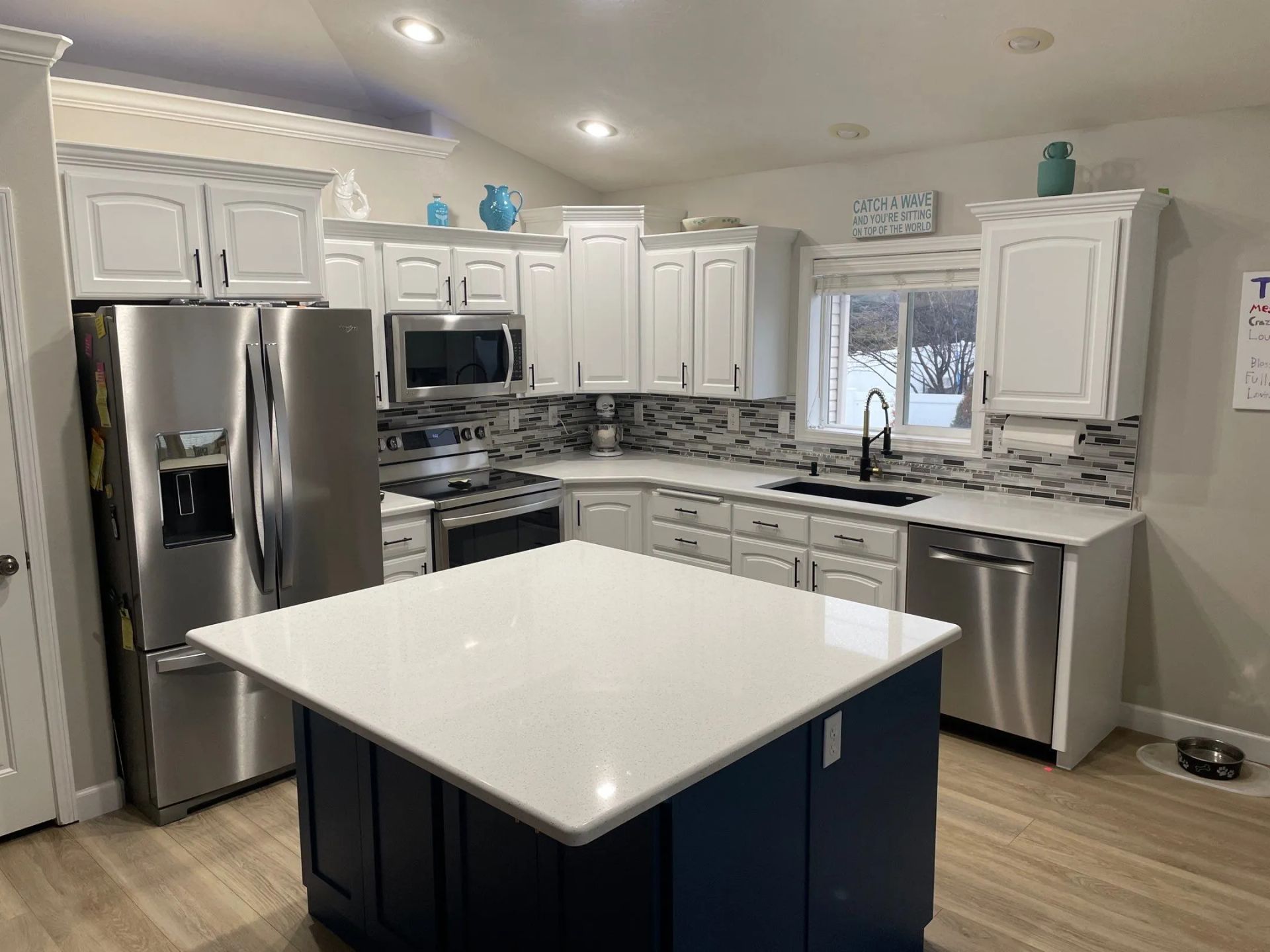 Bright modern kitchen with white cabinets, stainless steel appliances, and a blue island center
