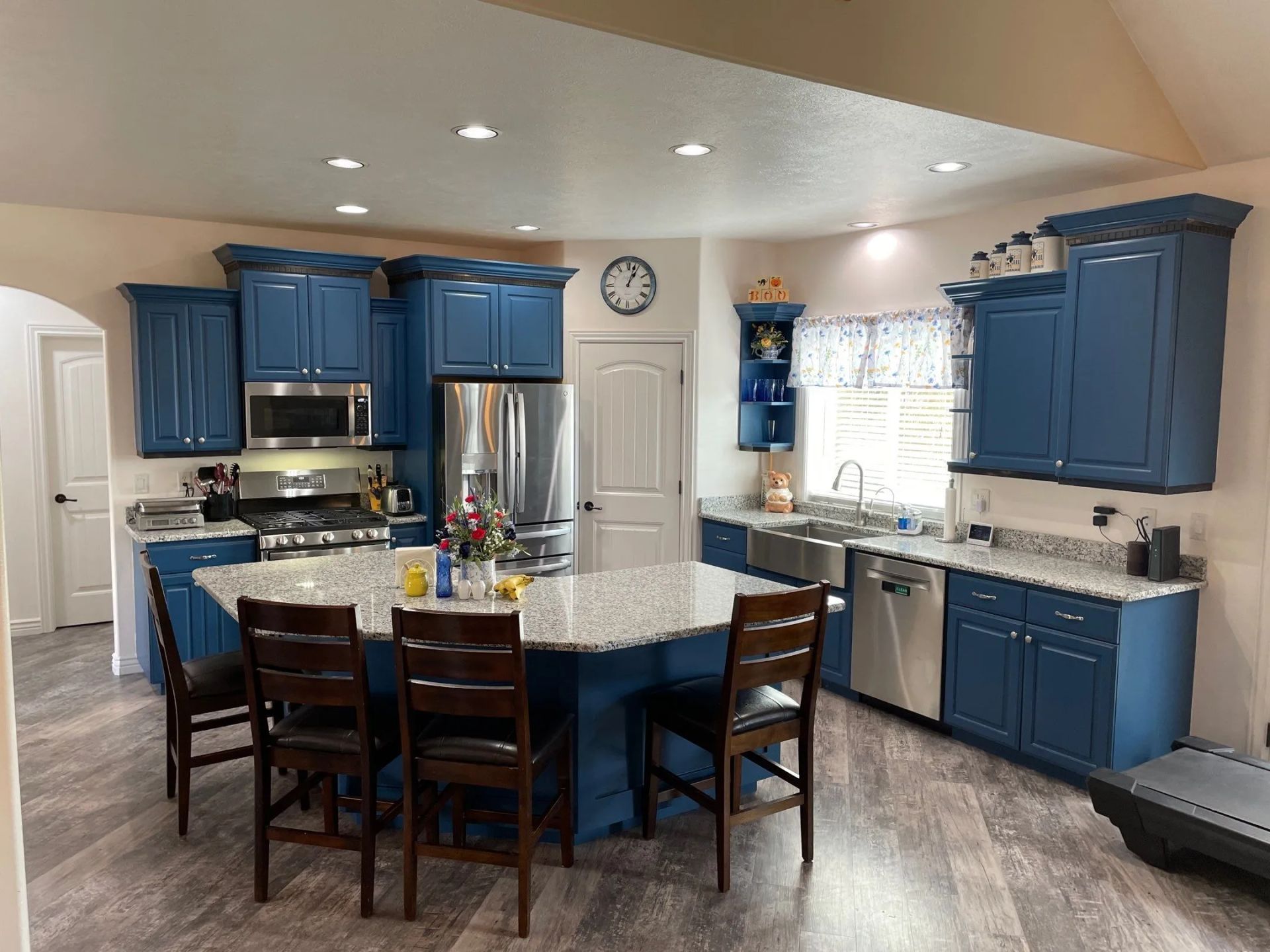 Bright kitchen with blue cabinets, granite island, dining table, and window over sink