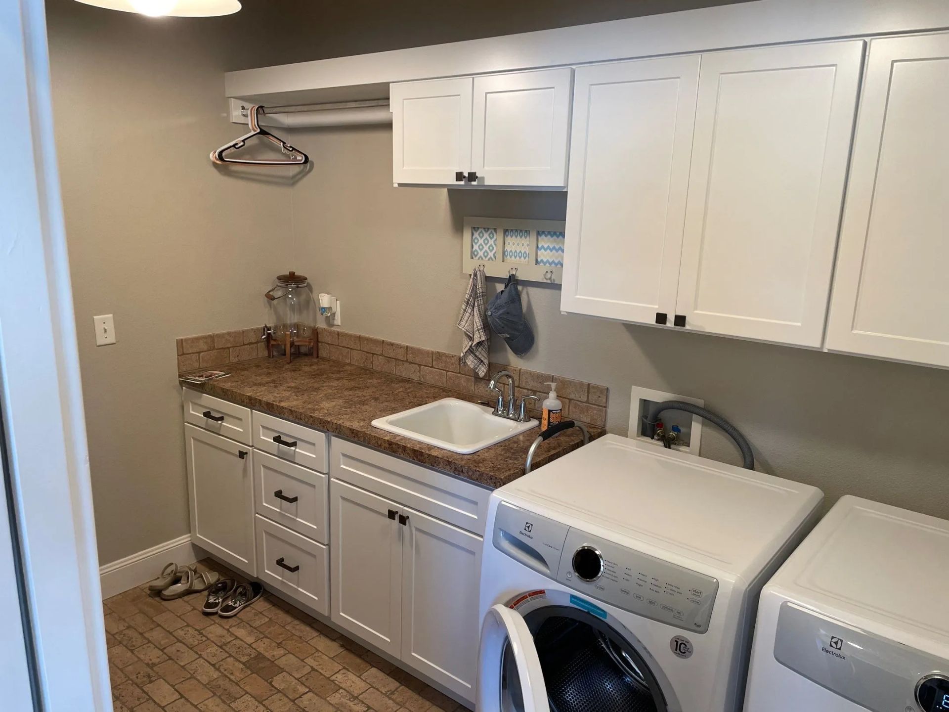 Laundry room with white cabinets, granite counter, sink, and stacked washer-dryer under wall cabinets
