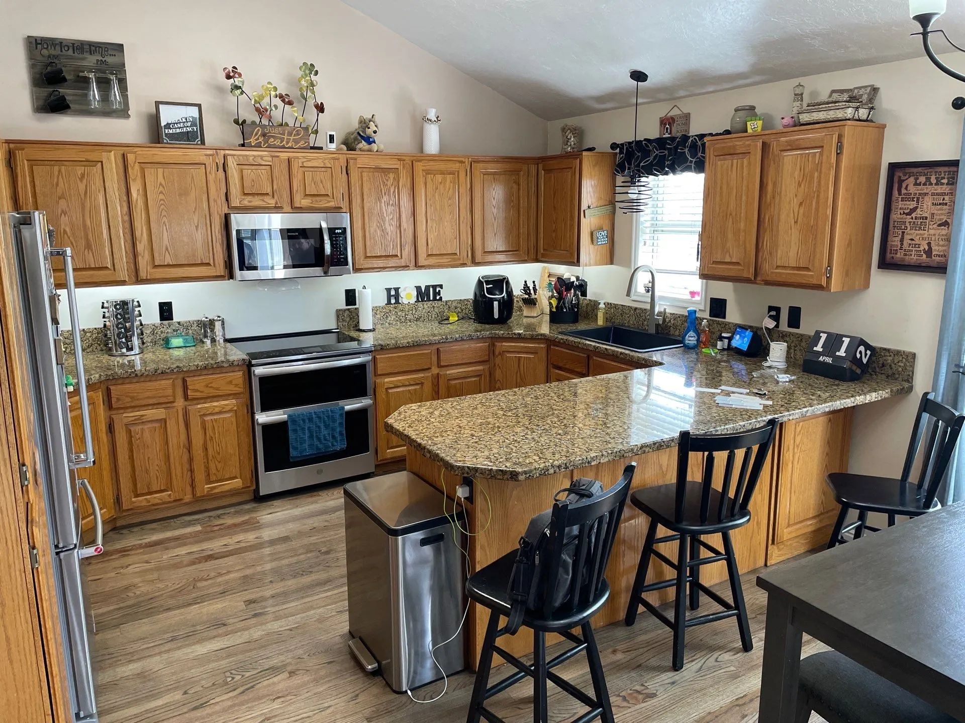 Bright kitchen with wooden cabinets, granite island, and stainless steel appliances