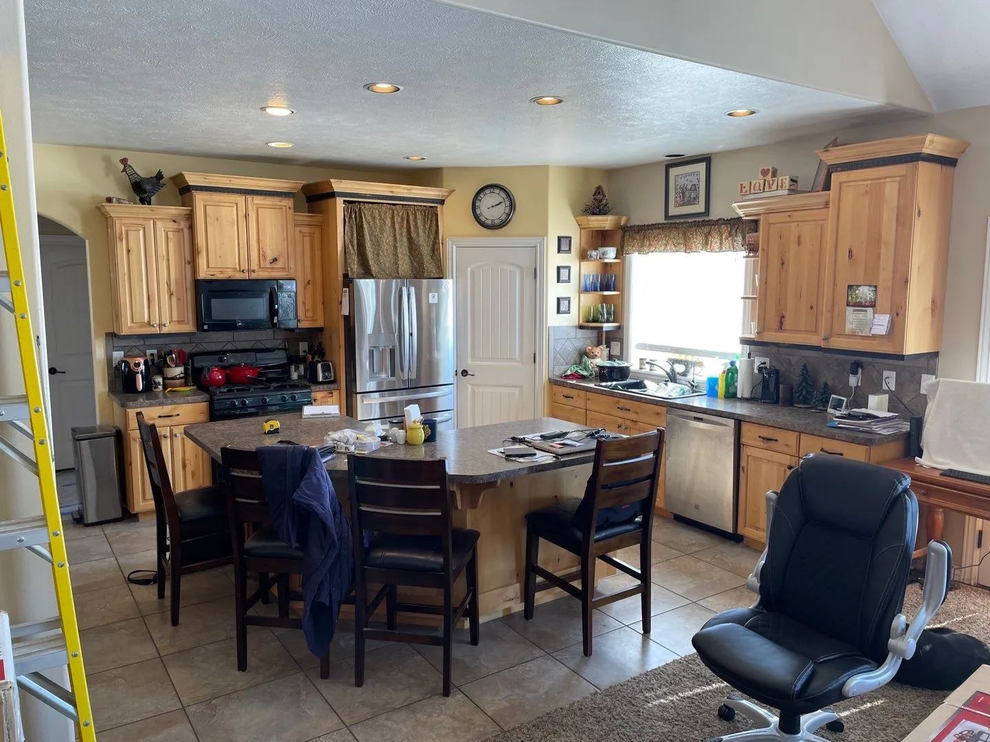 Kitchen and dining area with wood cabinets, island, and chairs, viewed from the living room