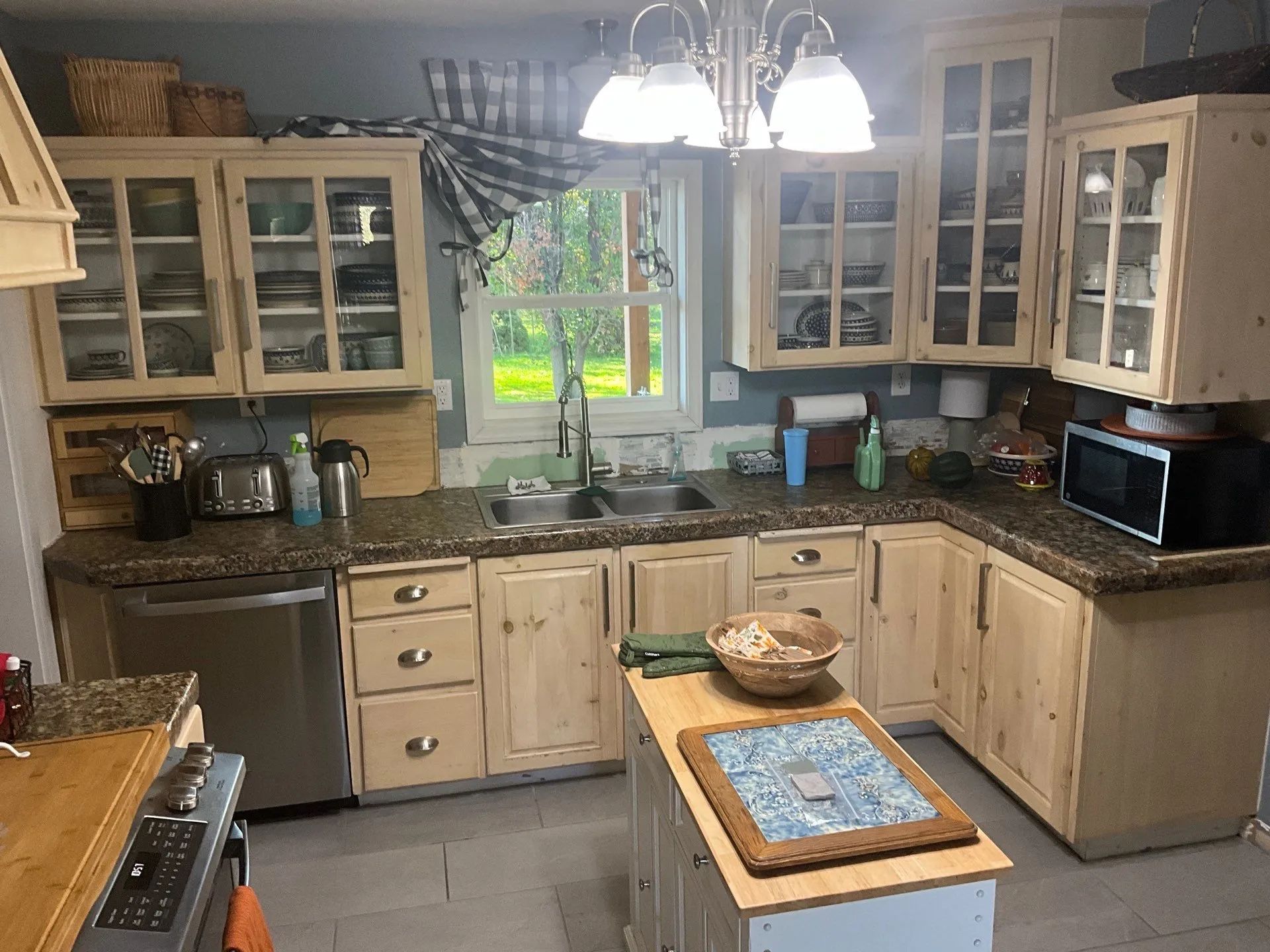 Bright kitchen with wood cabinets, granite counters, central island, and a window over the sink.
