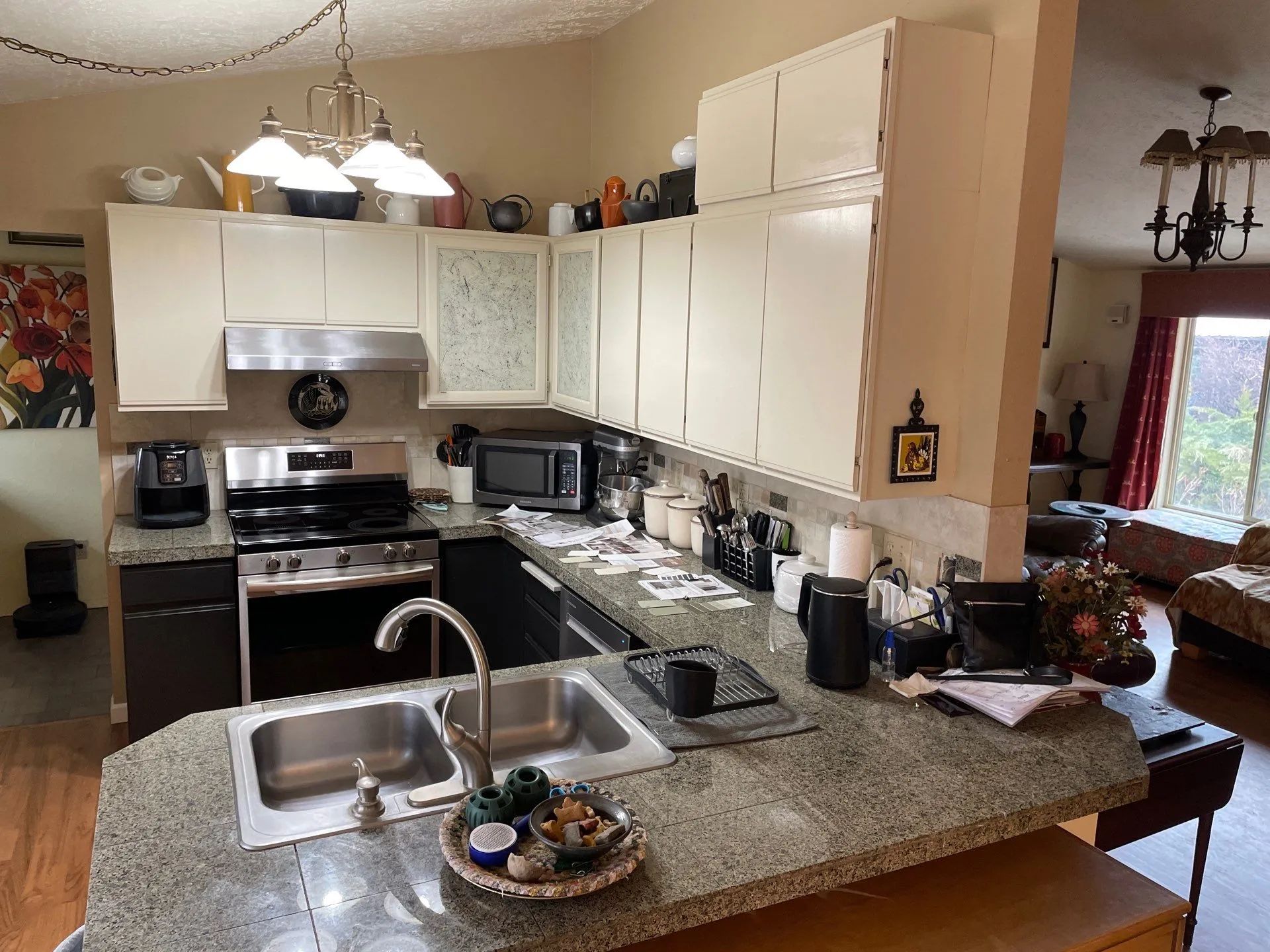 Kitchen with granite island, double sink, white cabinets, and stainless steel appliances.