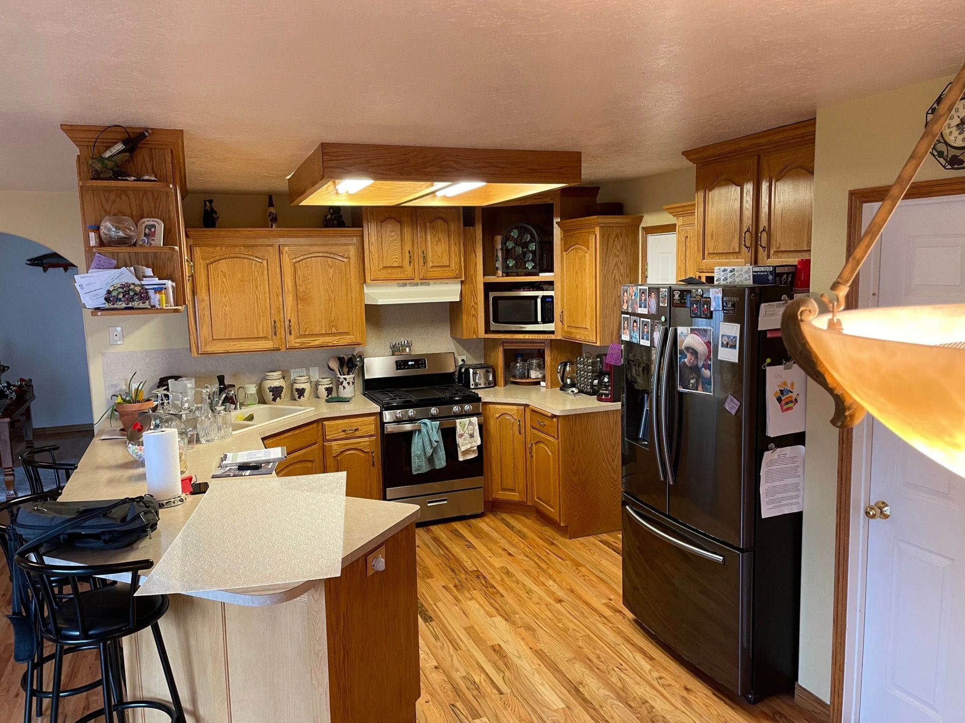 Kitchen with wooden cabinets, black appliances, and a central island under warm lighting