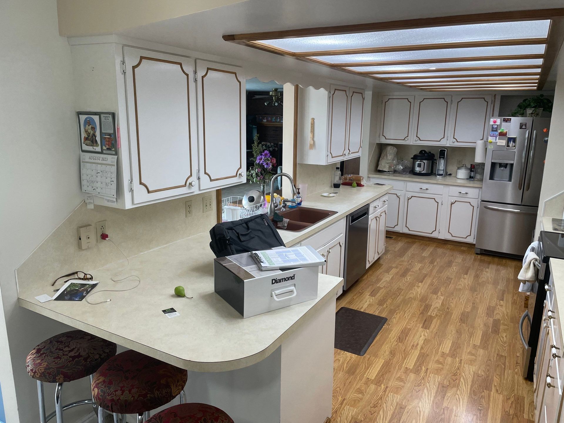Bright kitchen with white cabinets, curved island, wood floor, and stainless steel appliances